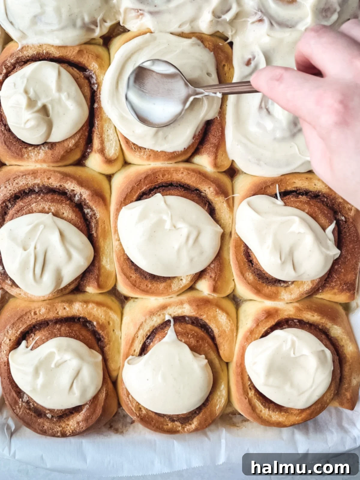 Golden Brown Butter Brioche Cinnamon Swirls 7 A brown butter brioche cinnamon roll topped with creamy white frosting, served on a white plate, ready to be enjoyed.