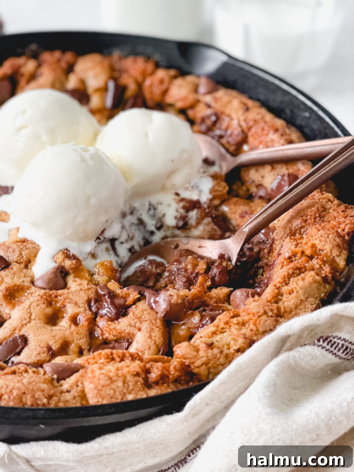 Gooey Brown Butter Toffee Skillet Cookie 9 Two hands reaching for a slice of warm brown butter toffee skillet cookie with melting ice cream.
