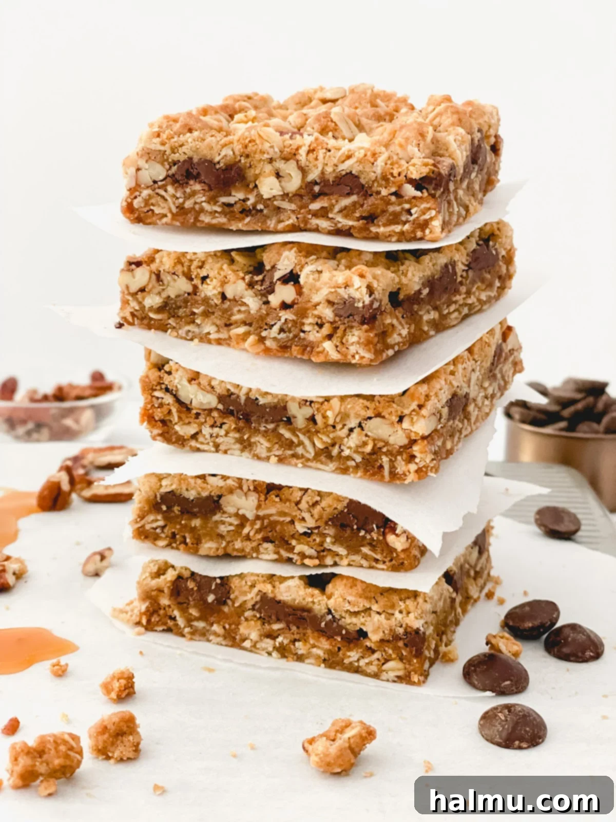 Stack of three Chocolate Caramel Pecan Bars, highlighting the distinct layers of oat base, caramel, pecans, chocolate, and crumbly oat topping.
