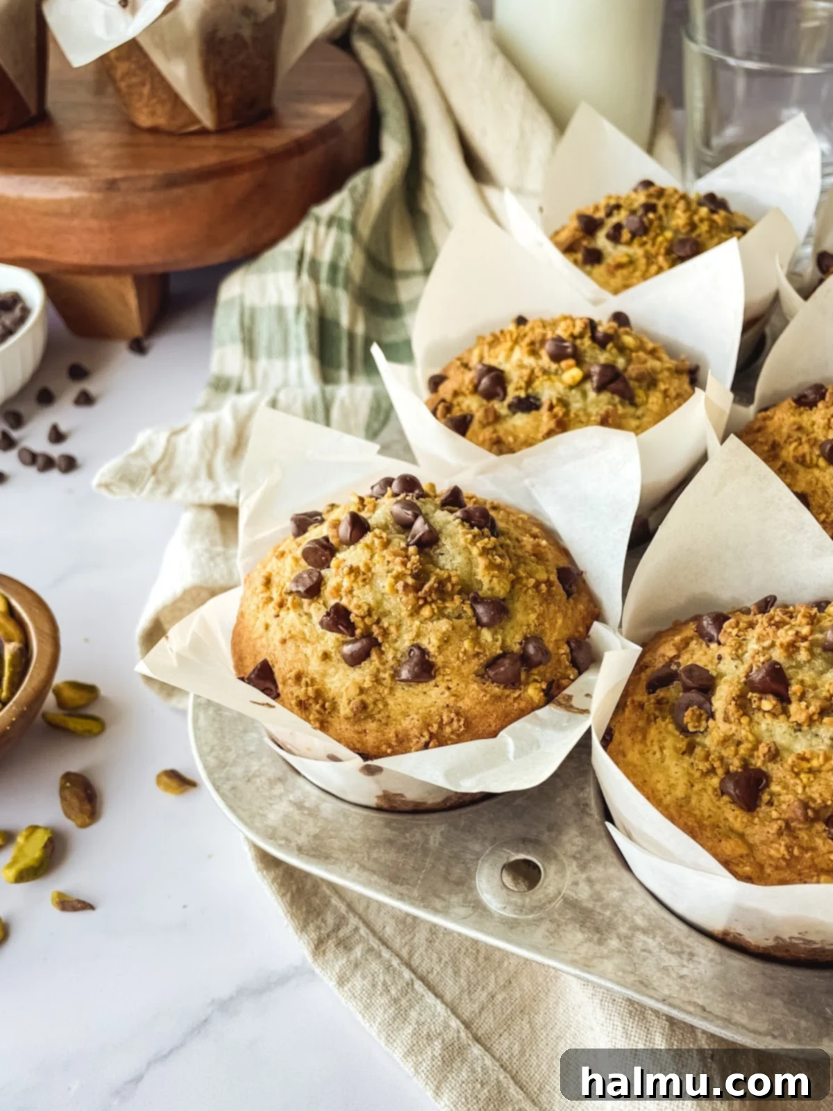 A stack of freshly baked Chocolate Chip Pistachio Muffins on a plate.