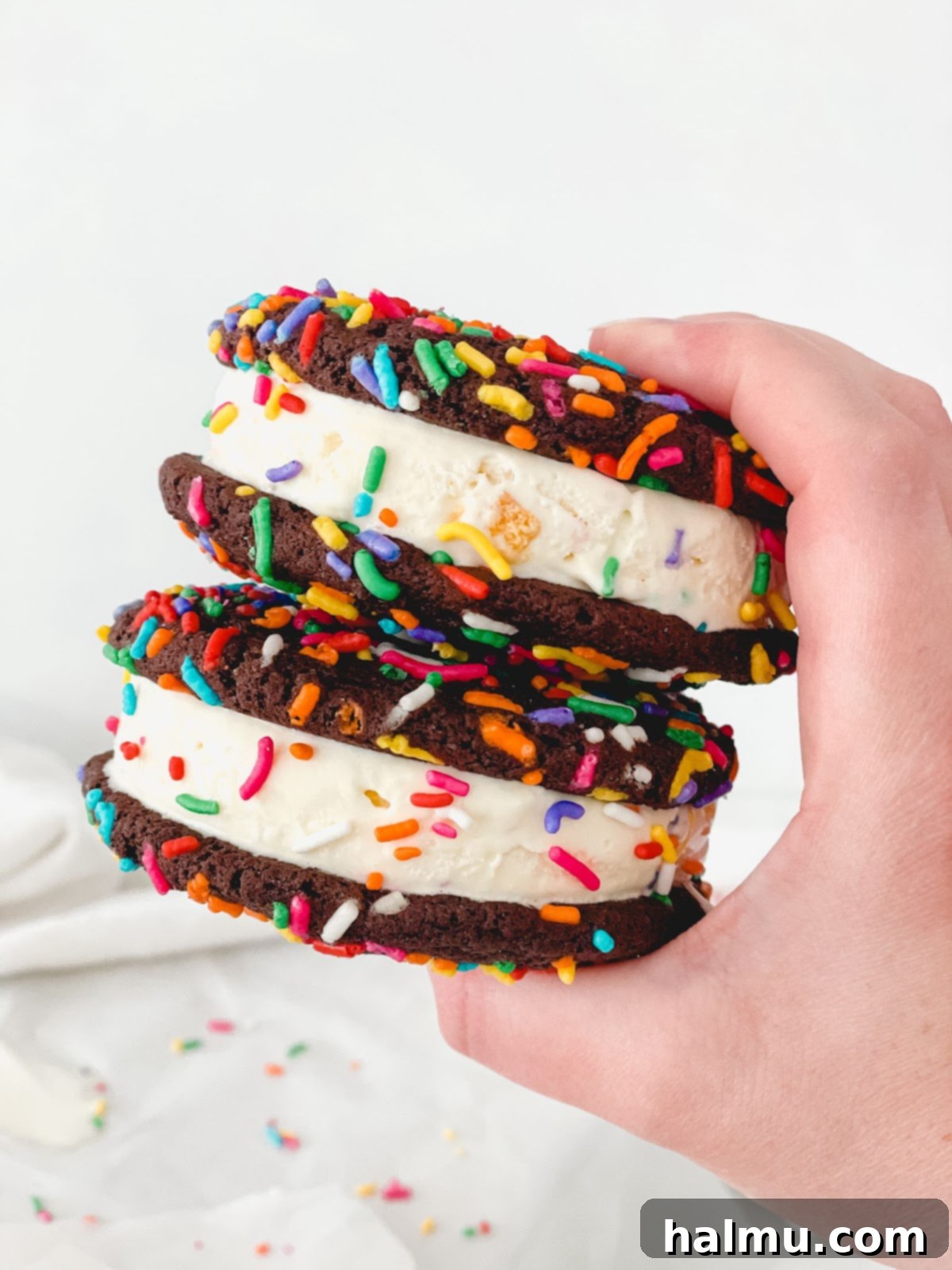 Chocolate Sprinkle Cookie Ice Cream Stacks 10 Several chocolate sprinkle cookie ice cream sandwiches arranged on a wooden board.