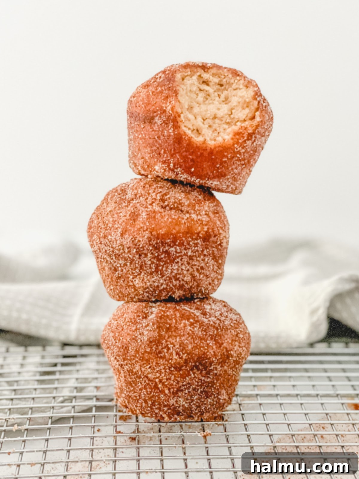 A stack of freshly coated Cinnamon Sugar Donut Muffins