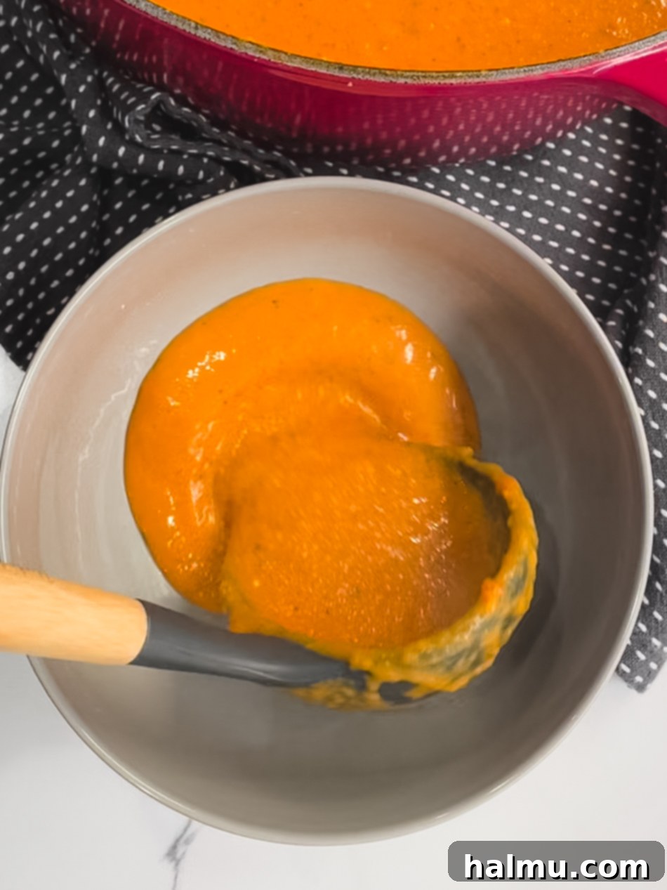 A top-down view of a Dutch oven filled with creamy tomato basil soup, ready for serving.