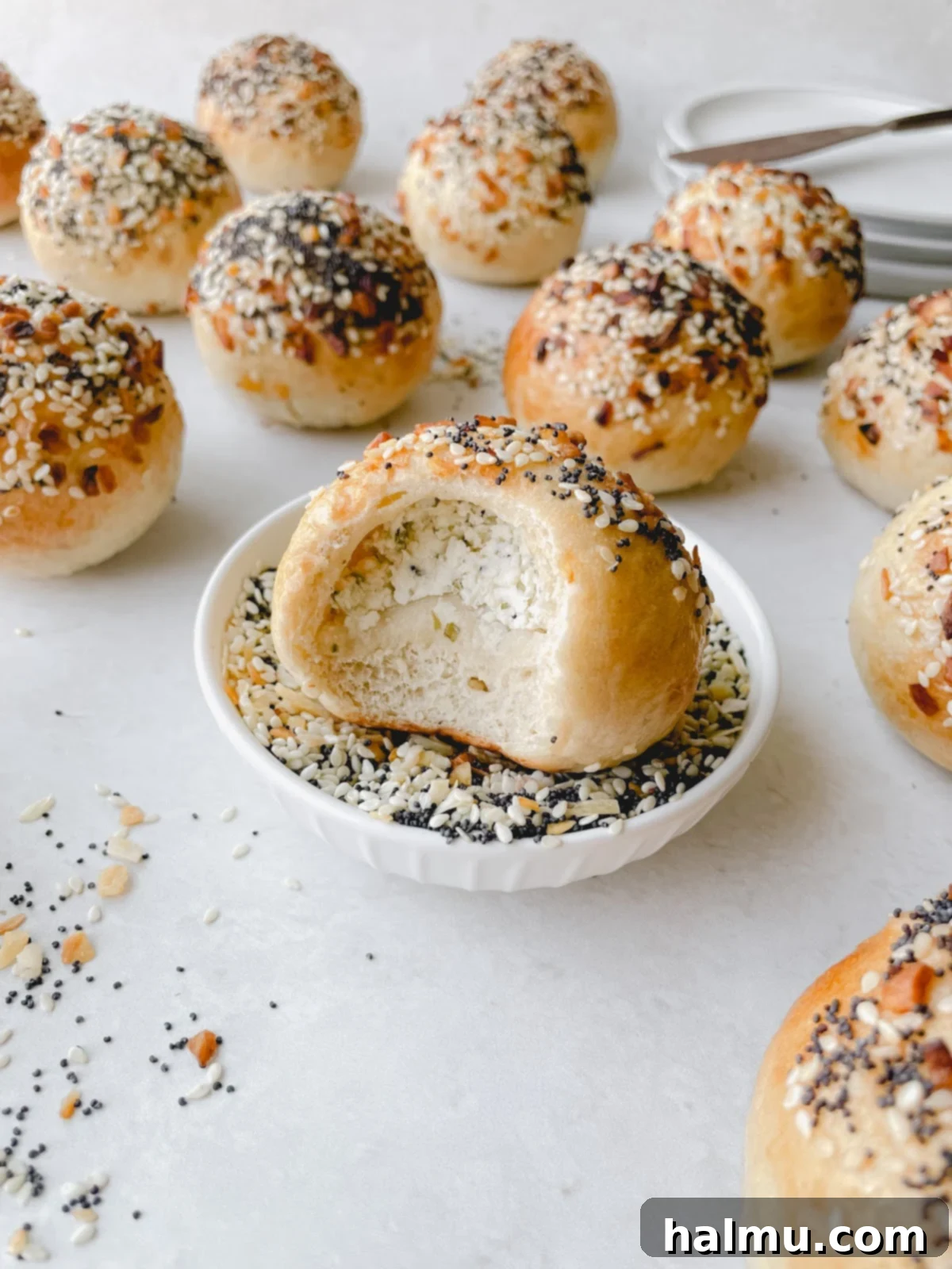 A cutting board with several Everything Bagel Bites, some cut in half to show the creamy filling