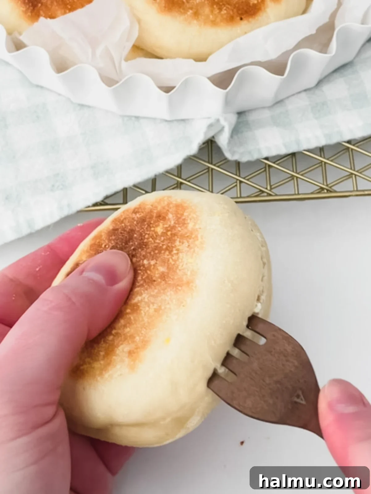 A fork splitting an English muffin in half