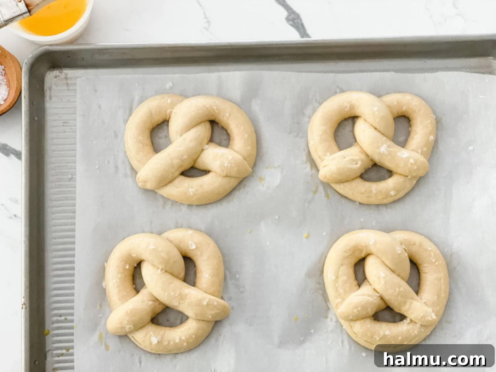 Close-up of a perfectly golden-brown homemade soft pretzel, showcasing its crisp exterior and flaky salt topping.