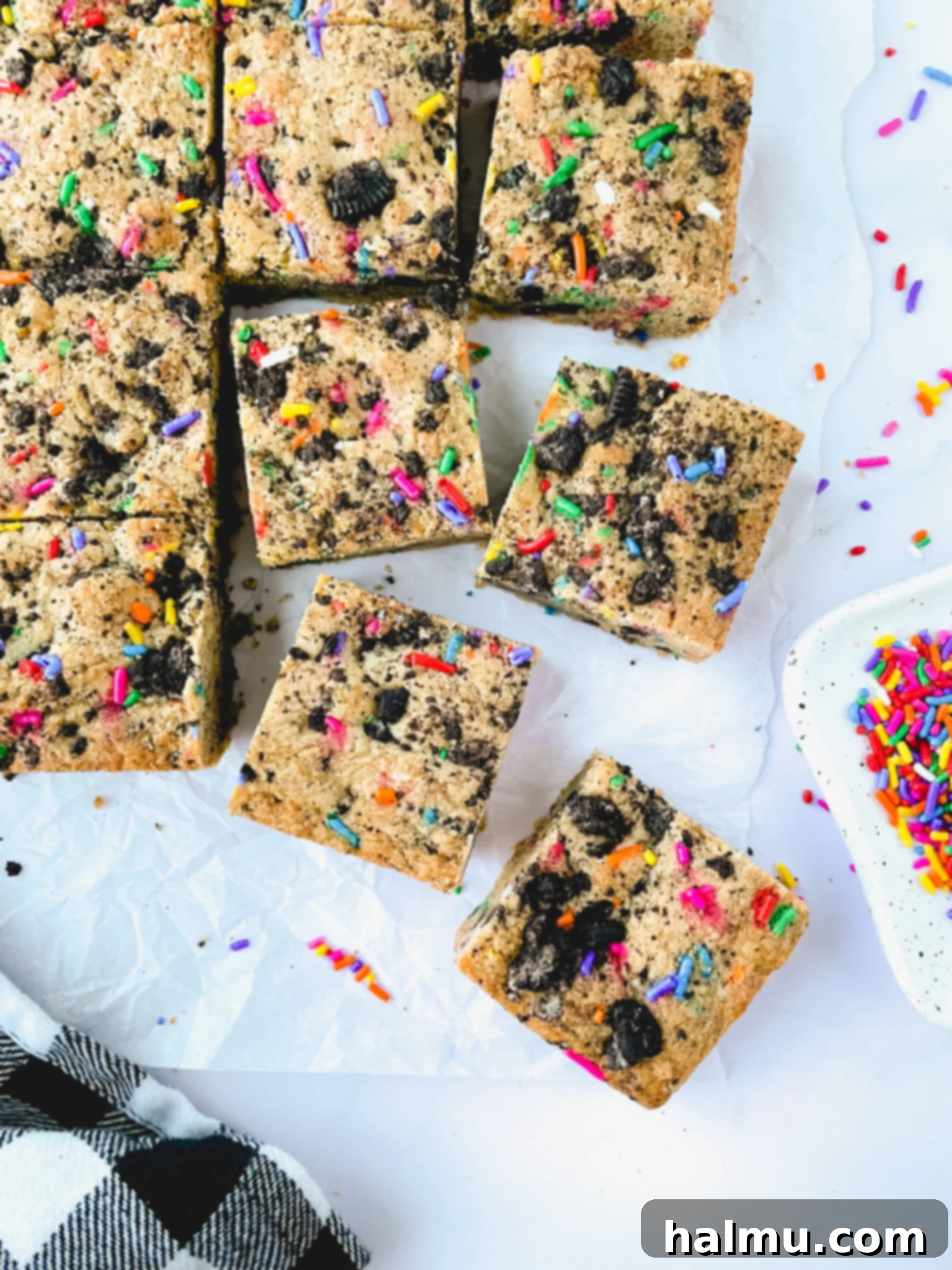 Party Oreo Funfetti Blondies 3 A stack of three Oreo Funfetti Blondies on a plate, with a bite taken from the top one, revealing its soft interior and the mix of Oreos and sprinkles.