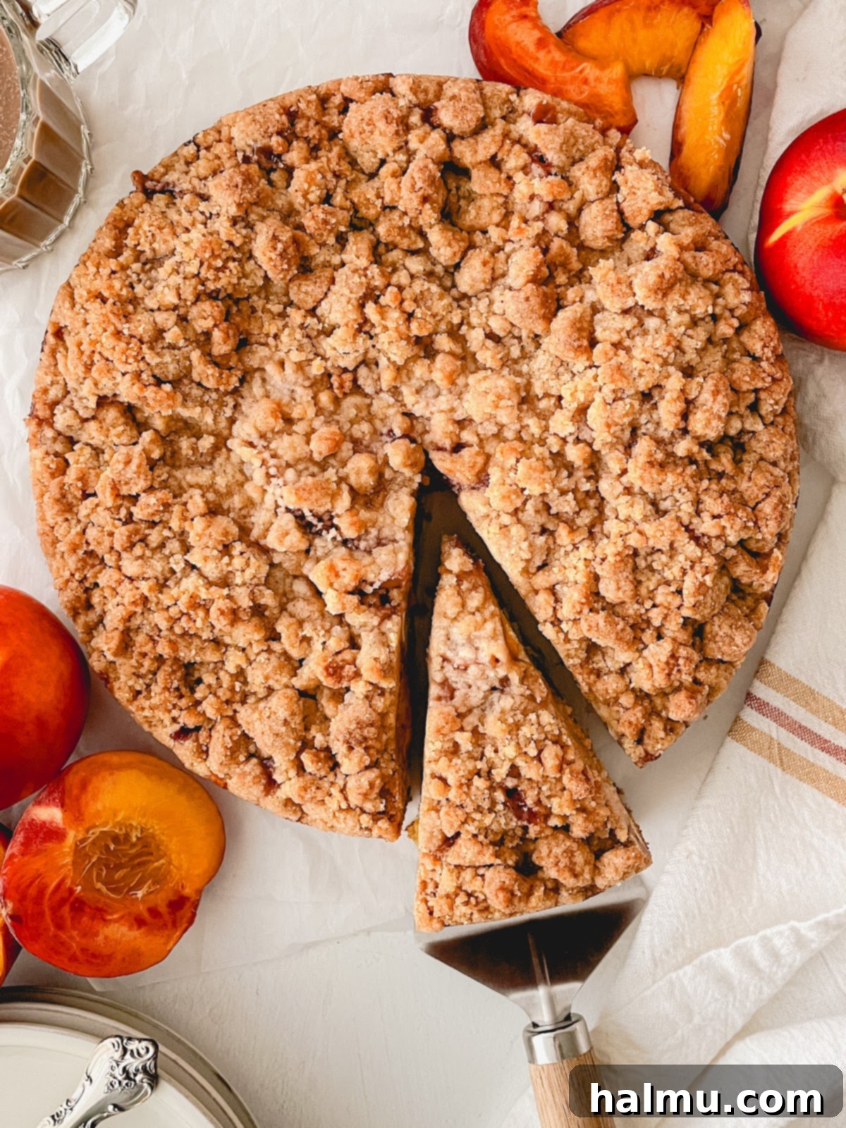 Heavenly Peach and Cream Crumb Cake 5 A slice of Peaches & Cream Crumb Cake on a white plate, showcasing all the beautiful layers: coffee cake, cream cheese, peaches, and crumb topping.
