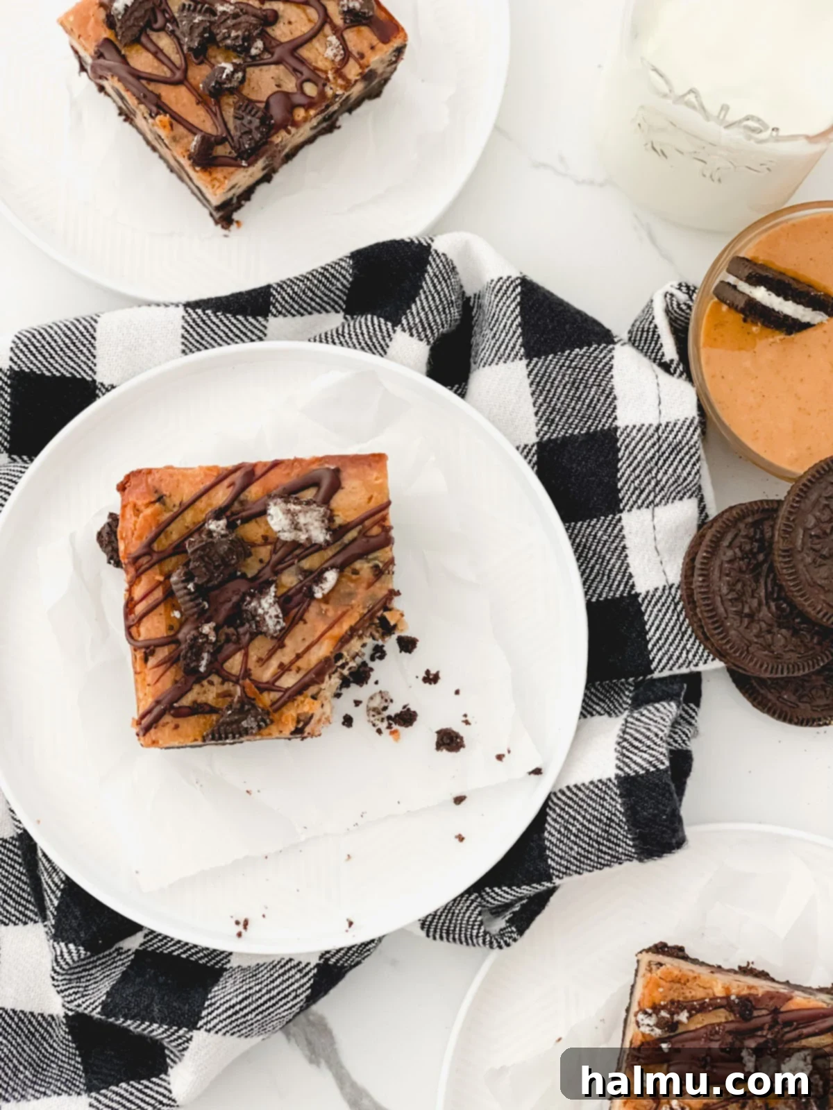 Four perfectly portioned Peanut Butter Oreo Cheesecake Bars stacked on a white plate, highlighting their layers.