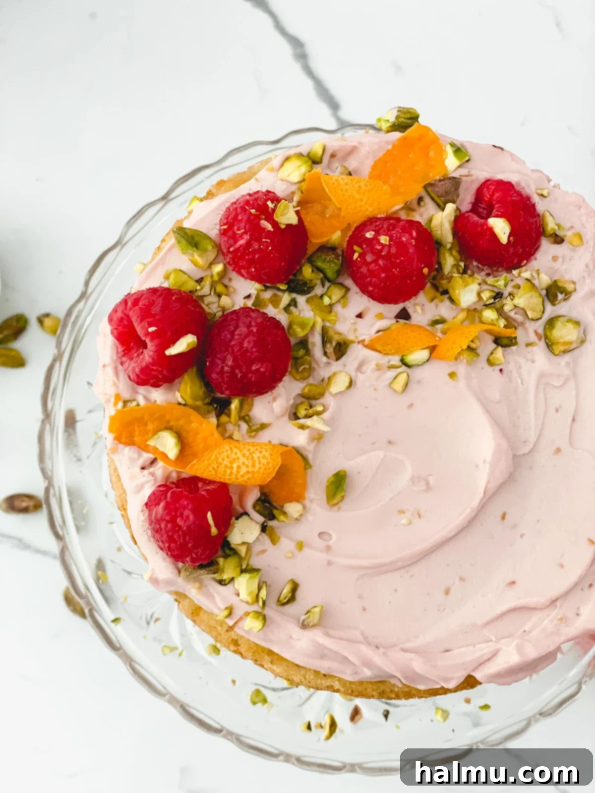 A slice of Raspberry Orange Pistachio Cake with fresh raspberries and orange zest.