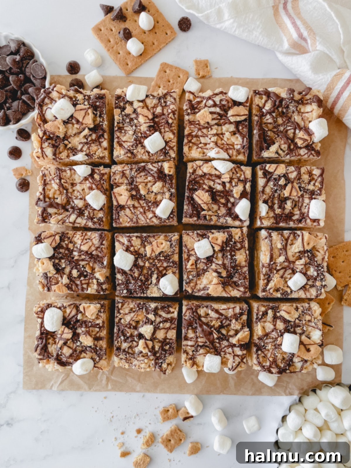 A hand reaching for a S'mores Rice Krispie Treat, highlighting its inviting texture and toppings.