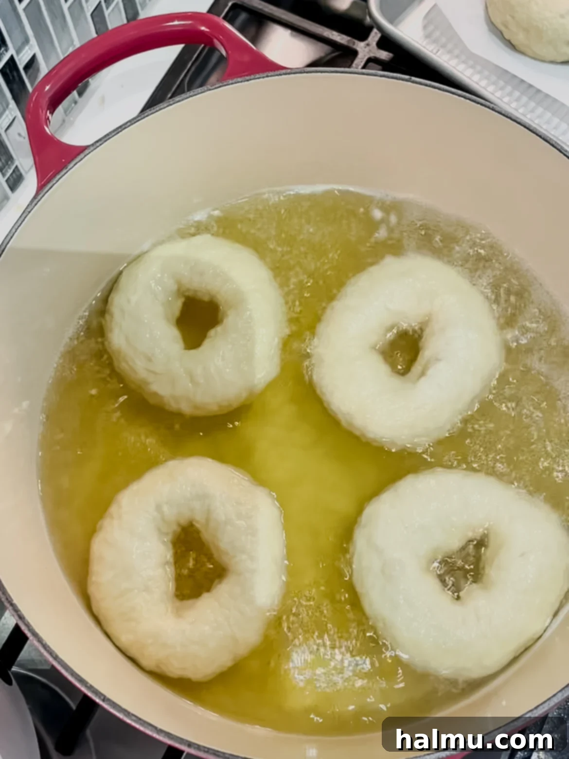 Deliciously Soft and Chewy Bagels 5 Bagels being boiled in a large pot with a honey water bath before baking