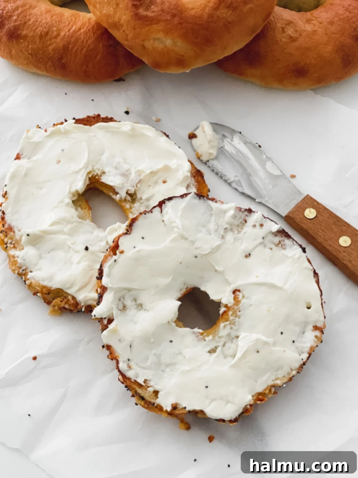 Deliciously Soft and Chewy Bagels 8 A toasted bagel half with cream cheese spread on it, ready to be eaten