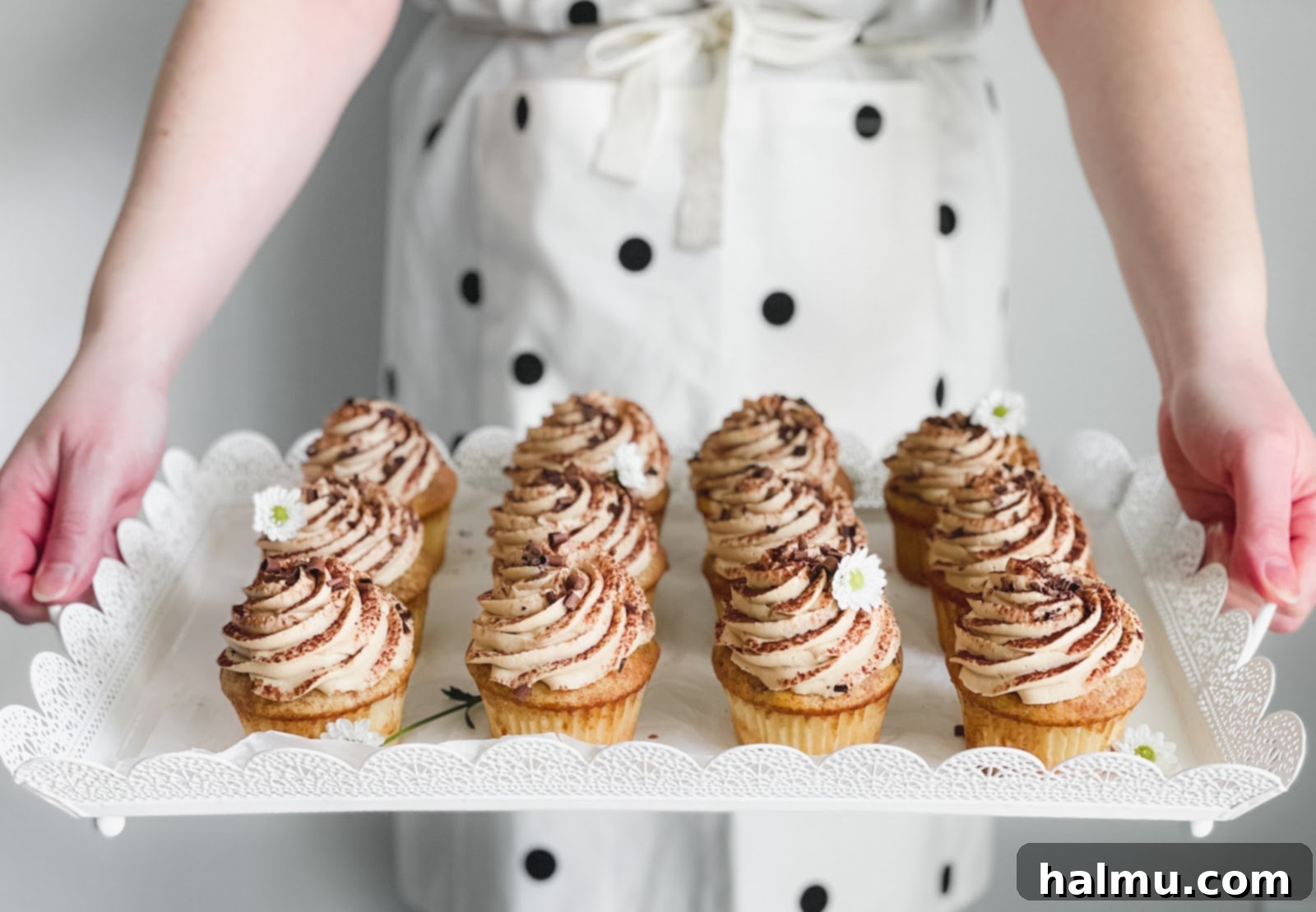 Decadent Tiramisu Cupcakes 3 A tray of freshly baked Tiramisu Cupcakes, some with frosting, others waiting for their topping.