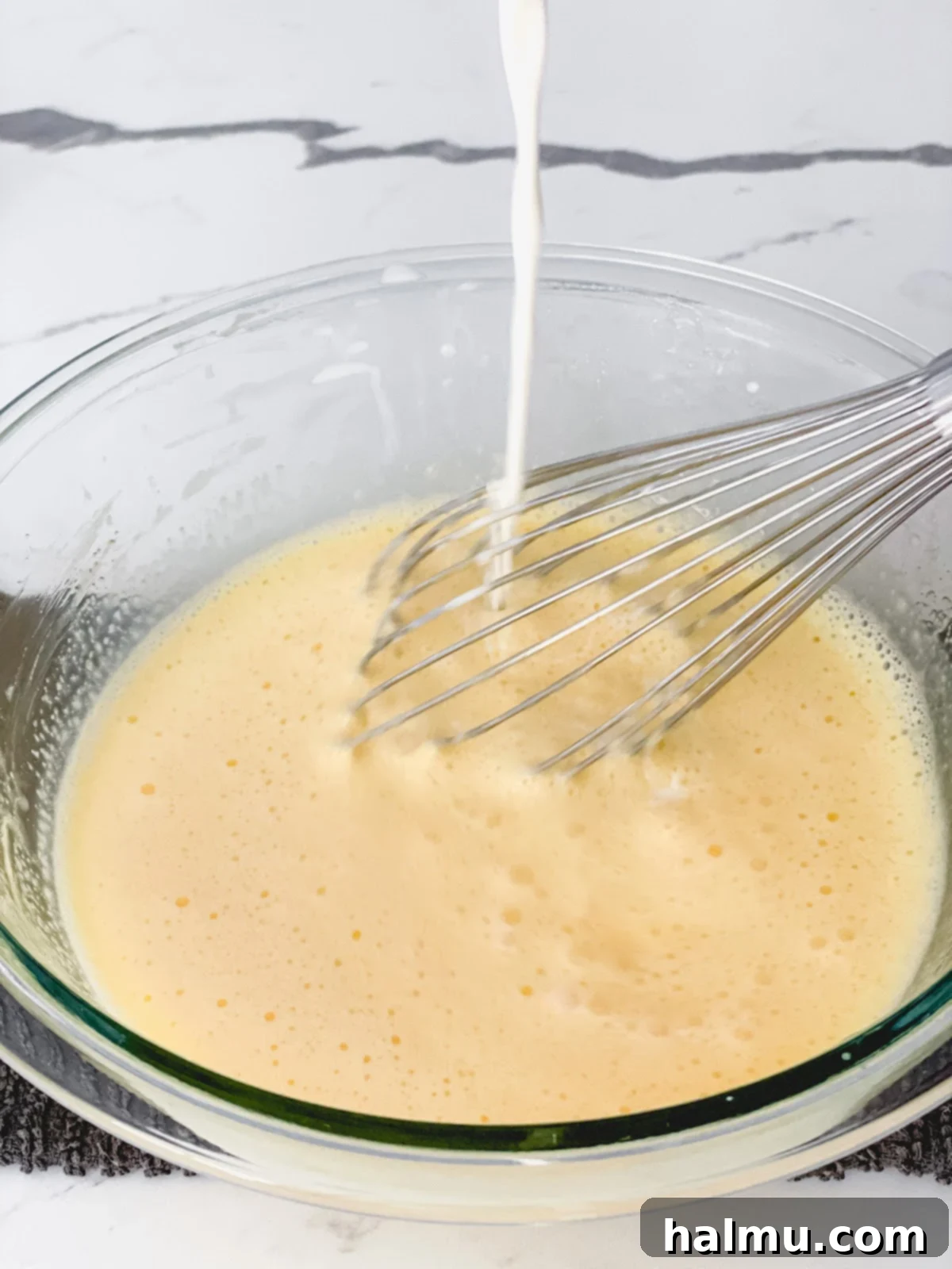 Rich Vanilla Bean Creme Brulee 5 The Crème Brûlée custard mixture being strained through a fine-mesh sieve into a bowl.