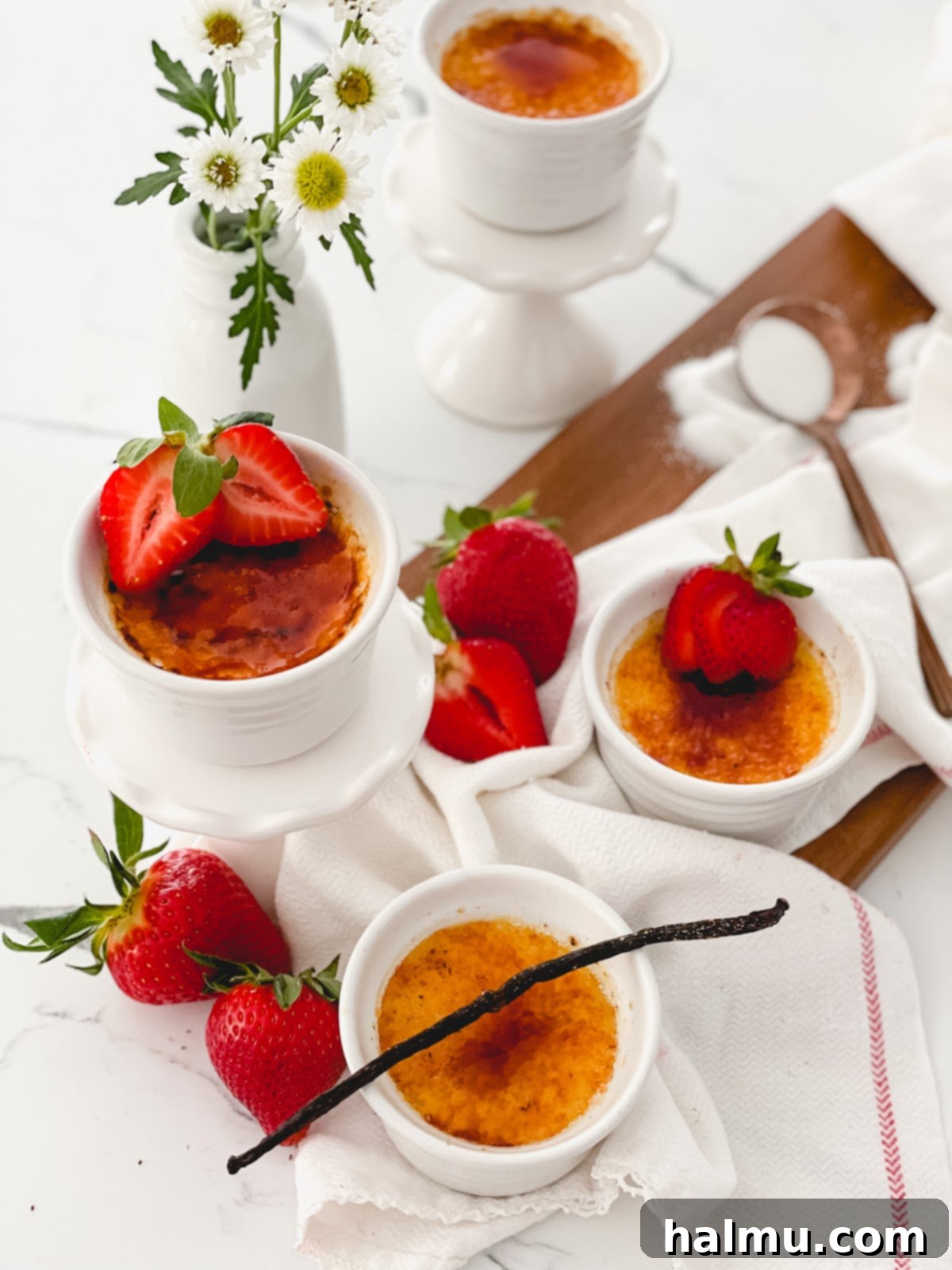 Rich Vanilla Bean Creme Brulee 9 Four ramekins of Vanilla Bean Crème Brûlée, two with untouched caramelized tops and two with spoons broken through the crust, revealing the creamy custard.