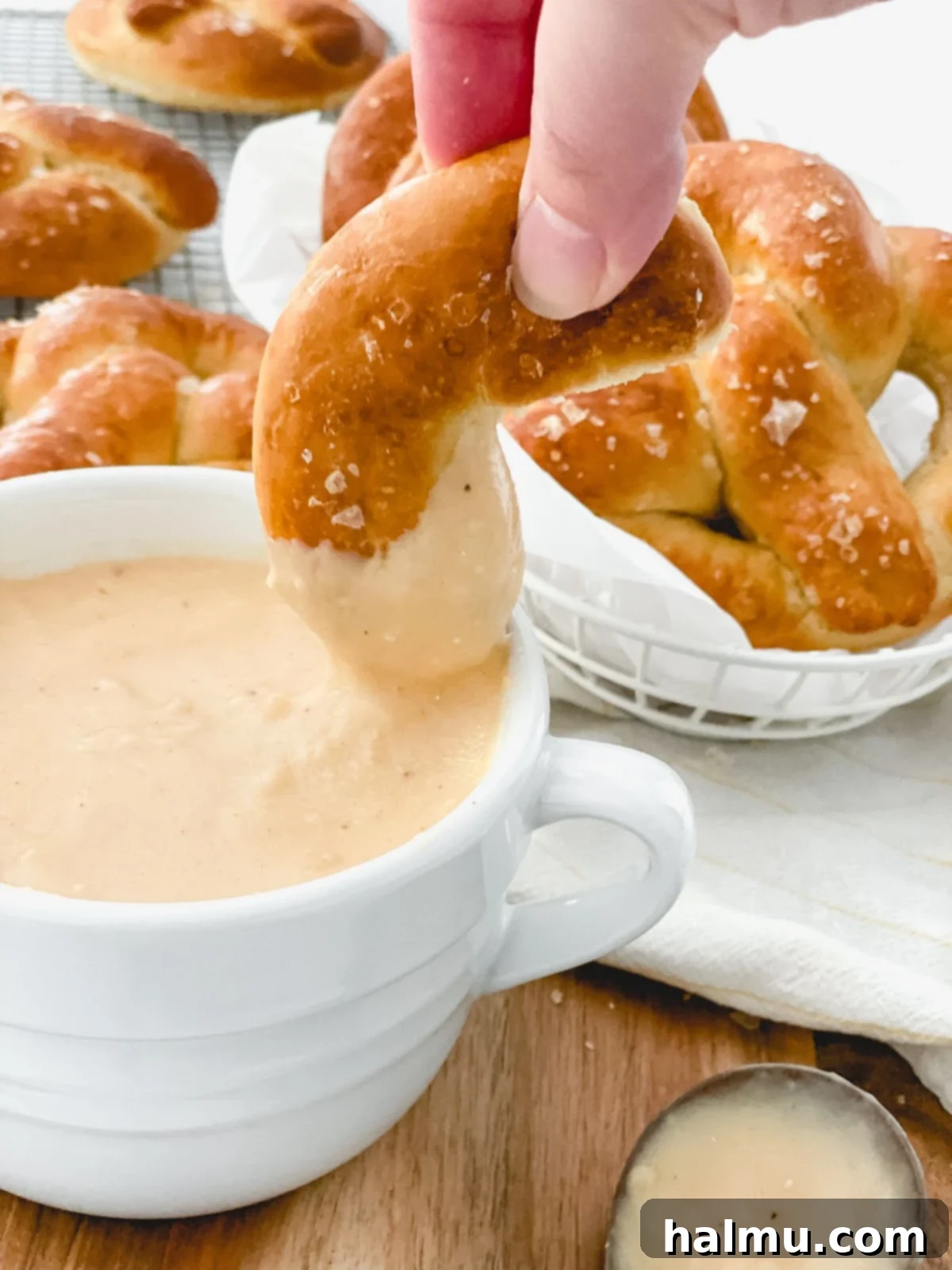 Homemade soft pretzels being dipped into Warm Beer Cheese Dip