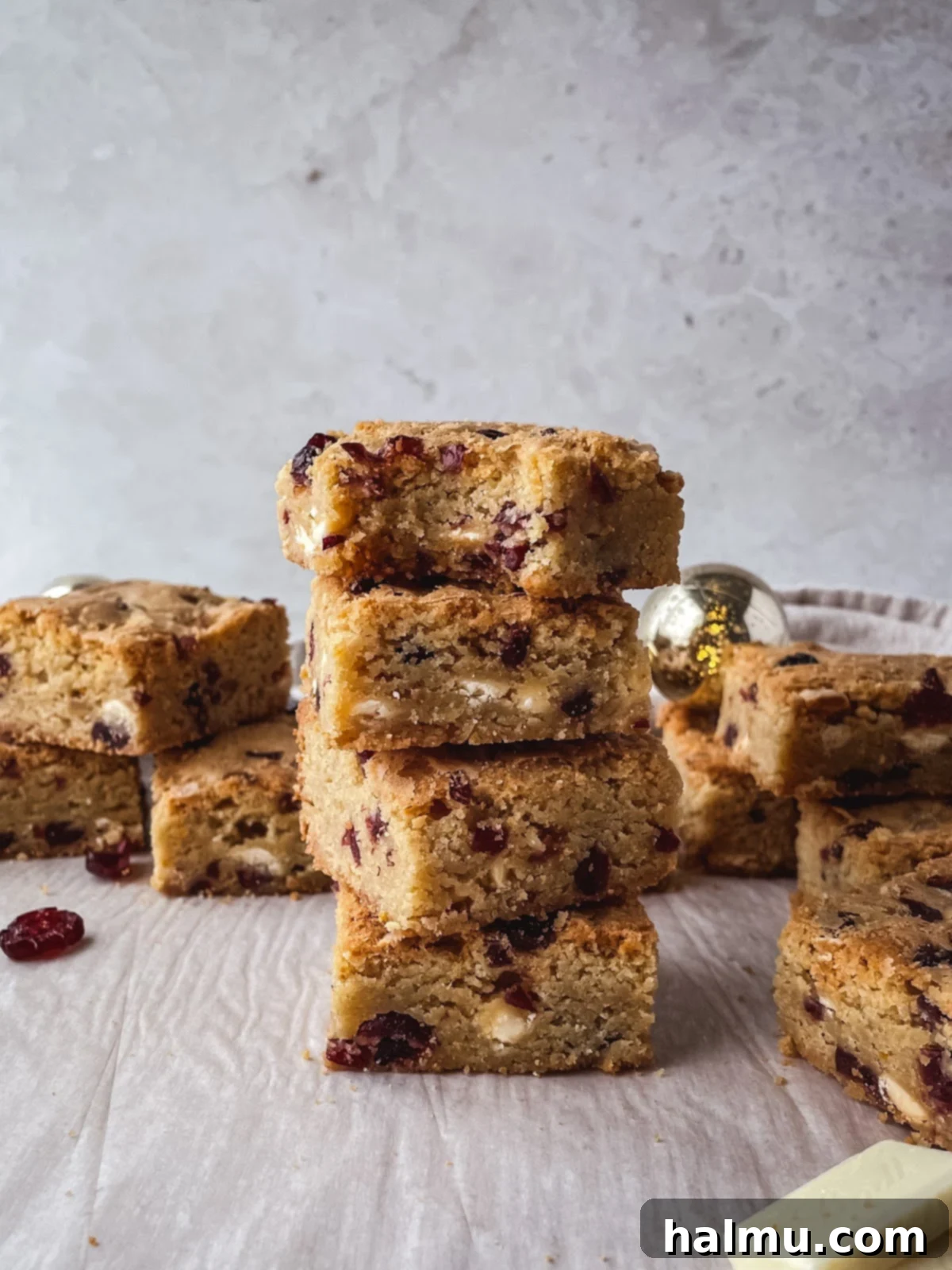 A beautiful arrangement of White Chocolate Cranberry Blondies on a rustic wooden board, ready to be enjoyed.