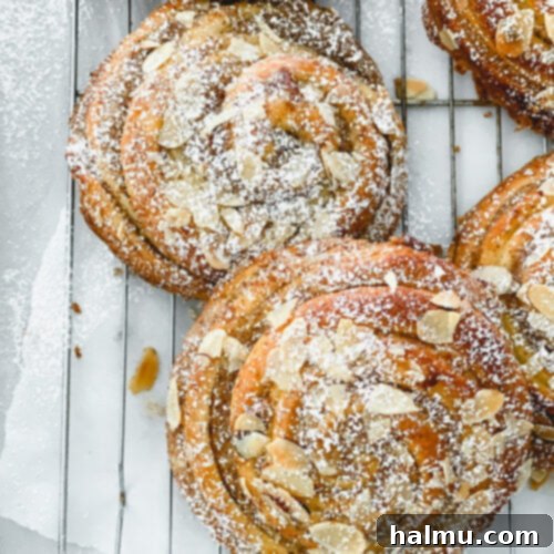 A stack of perfectly baked Almond Cream Brioche Buns, dusted with powdered sugar and ready to be served.
