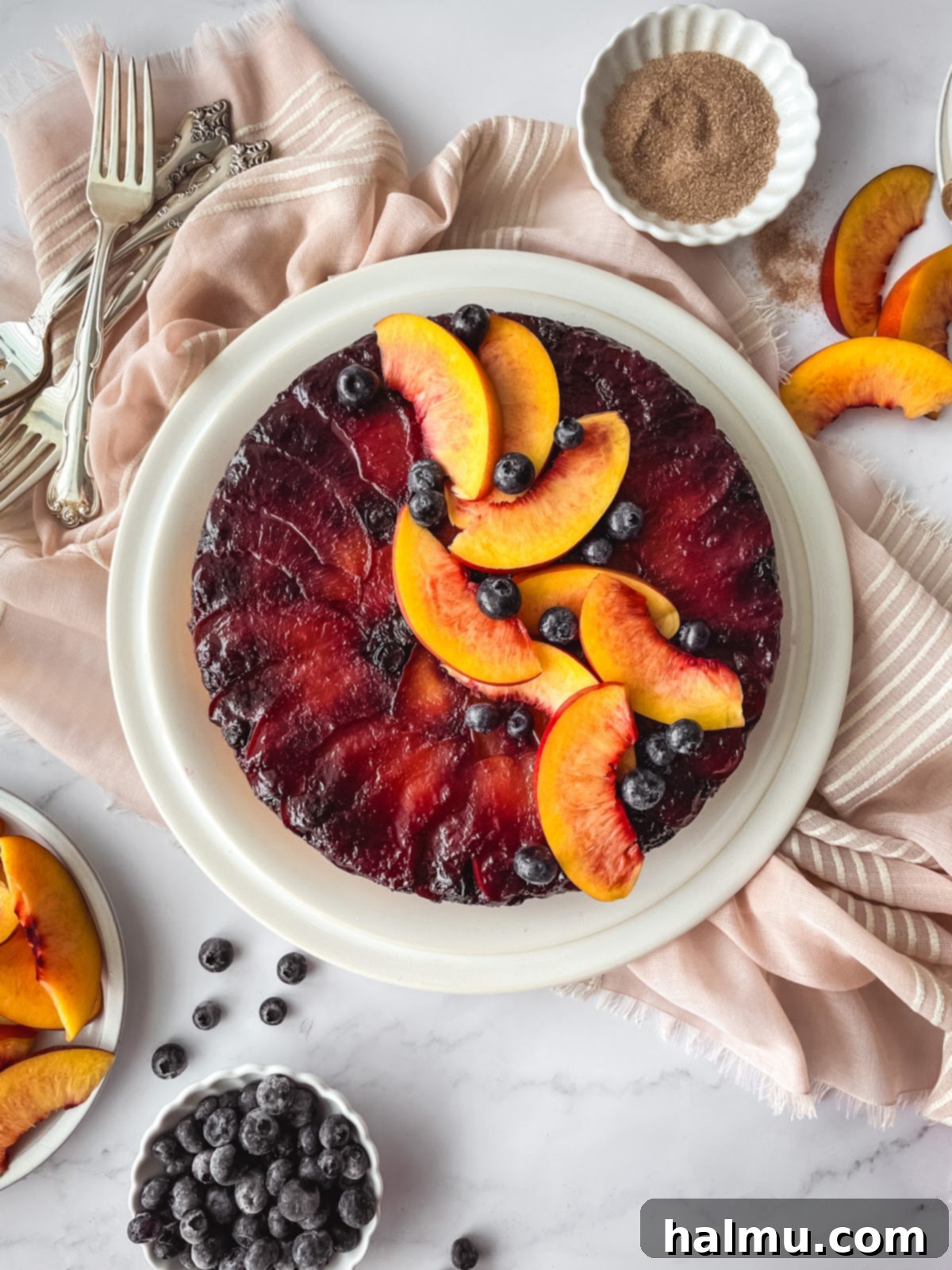 A full Blueberry Nectarine Upside-Down Cake on a serving plate, ready to be sliced.