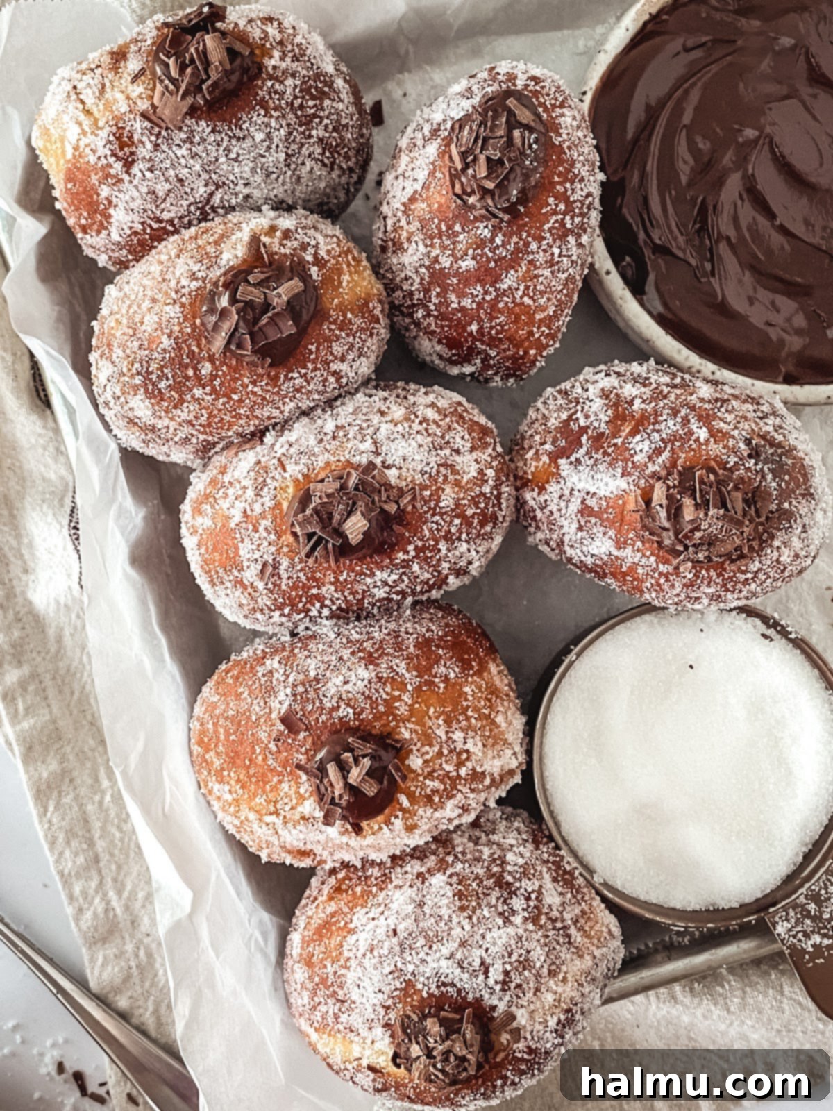 Decadent Chocolate Custard Brioche Donuts 7 Three perfectly fried and sugared brioche donuts, ready for filling, resting on a cooling rack.