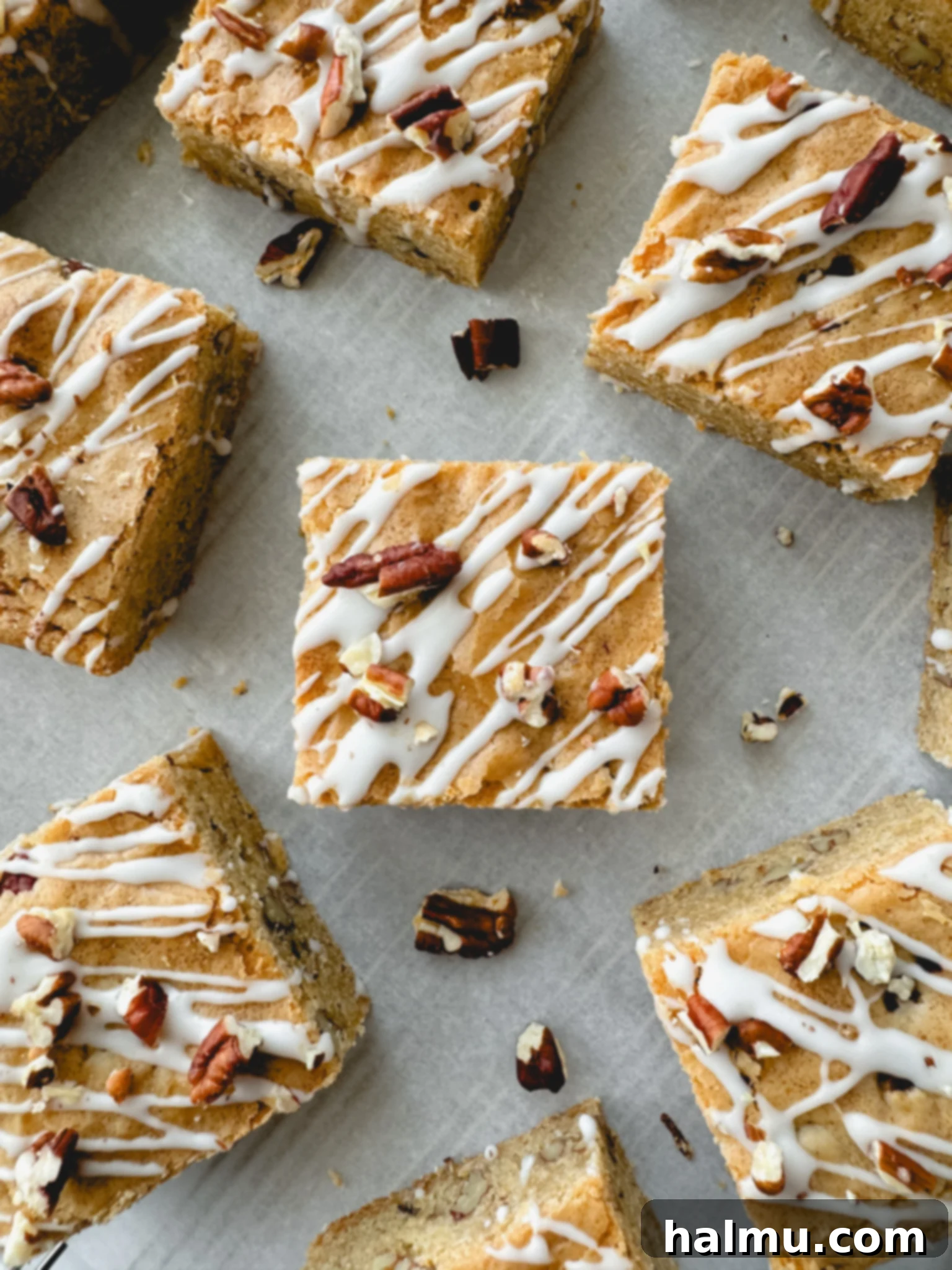 Stack of Maple Pecan Blondies, with a drizzle of maple glaze and chopped pecans on top, showcasing their tempting appearance.