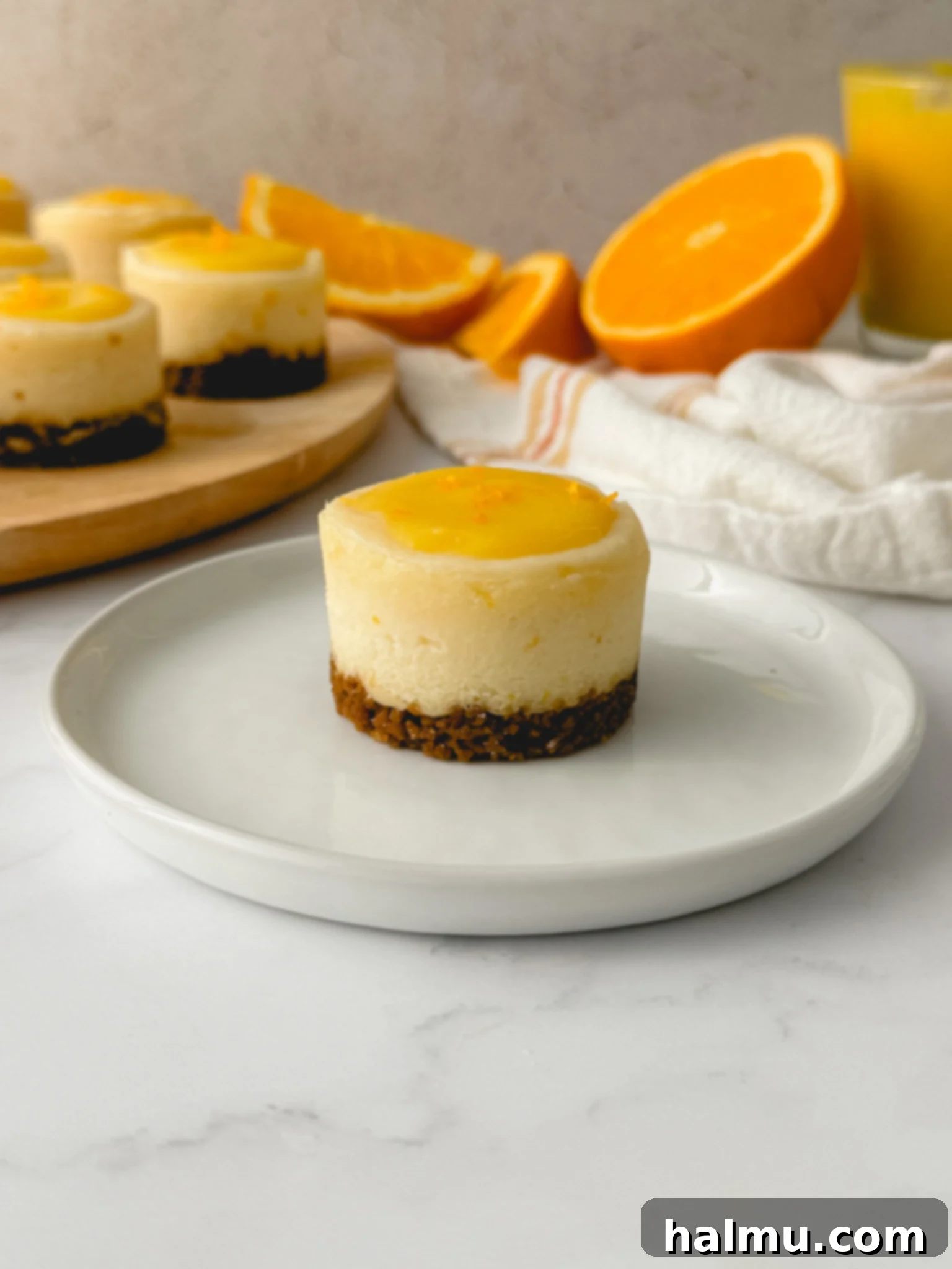 A close-up of a single mini orange cheesecake with its perfect layers of crust, filling, and curd, ready to be enjoyed.