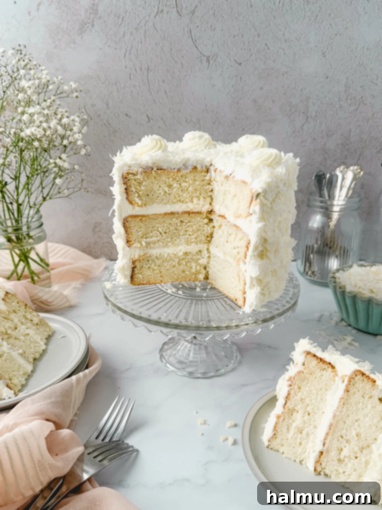 A stunning three-layer white coconut cake, beautifully frosted and covered in large coconut flakes, perfect for a Spring celebration.