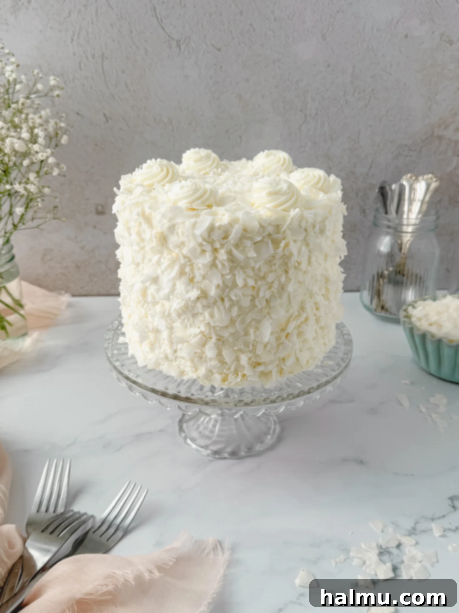 A vibrant coconut cake decorated with fresh berries and sprigs of mint, ready for serving.