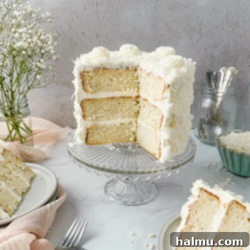 Delicious coconut layer cake with almond chantilly frosting, adorned with coconut flakes.