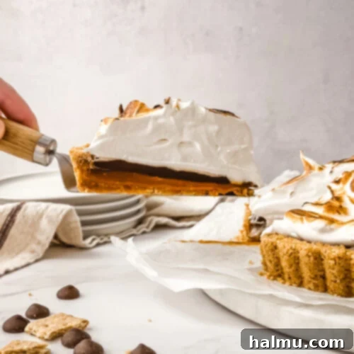 A slice of the Salted Caramel S'mores Tart, showing off the perfectly toasted meringue, gooey caramel, and rich chocolate.