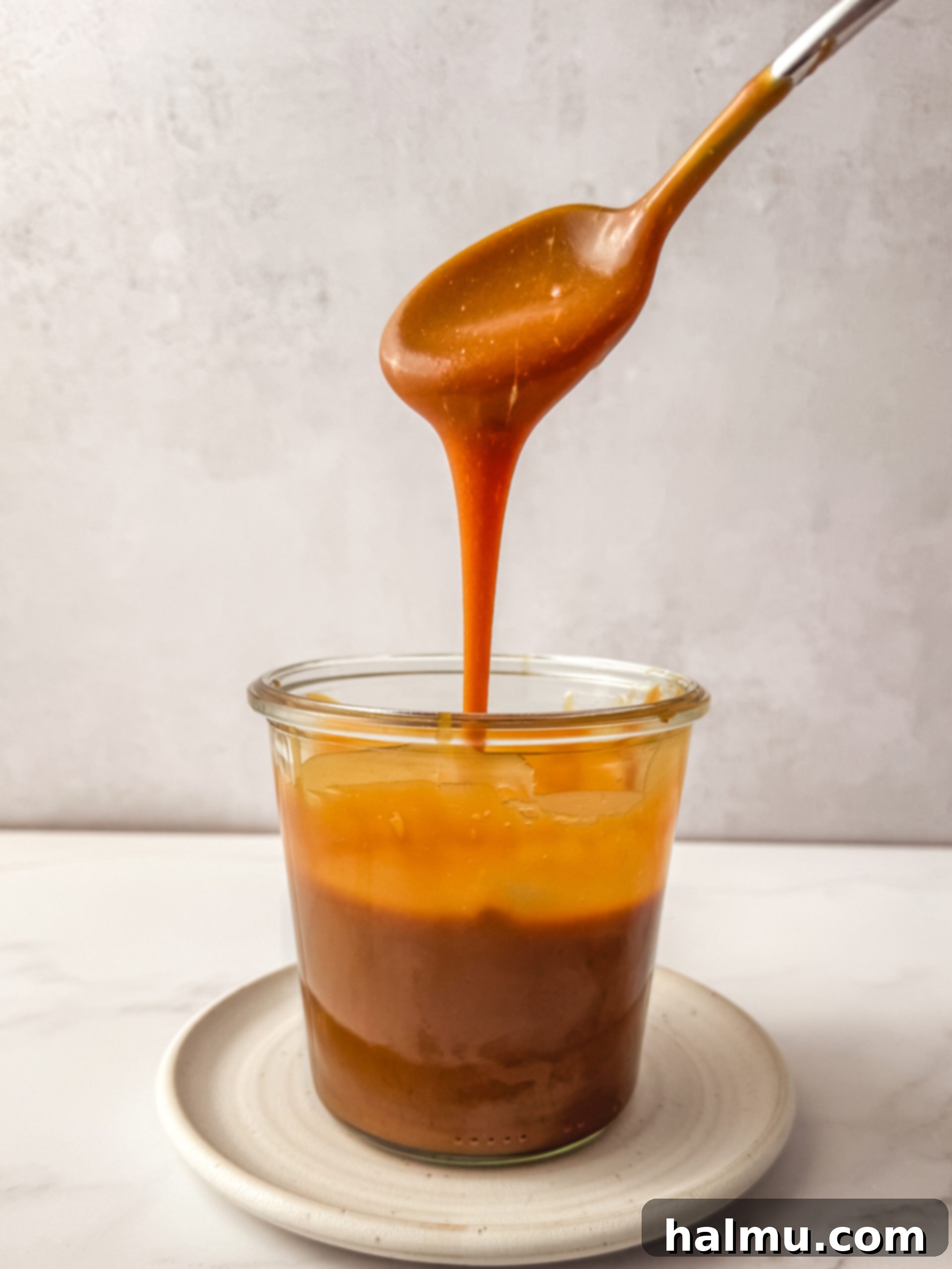 Two jars of homemade caramel and a small bowl of sugar