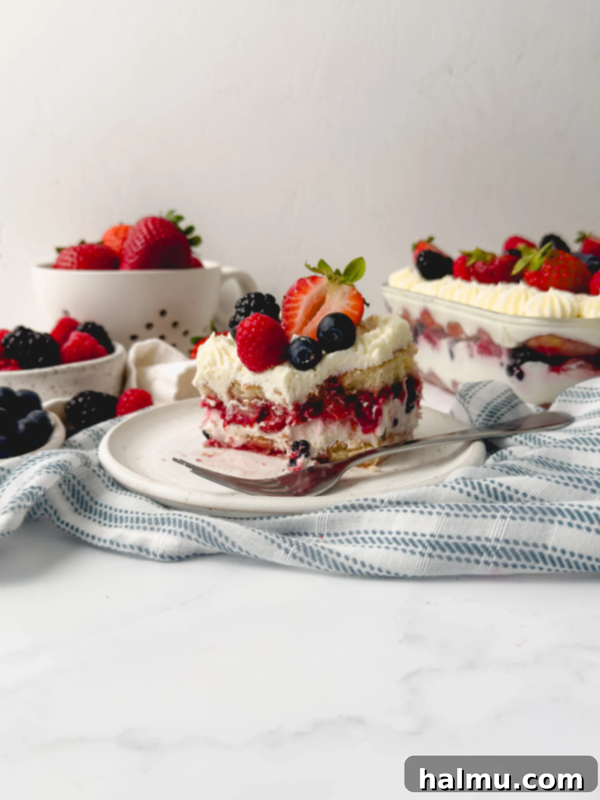 Delicious Berry Chantilly Tiramisu in a glass baking dish, topped with fresh berries and whipped cream swirls.
