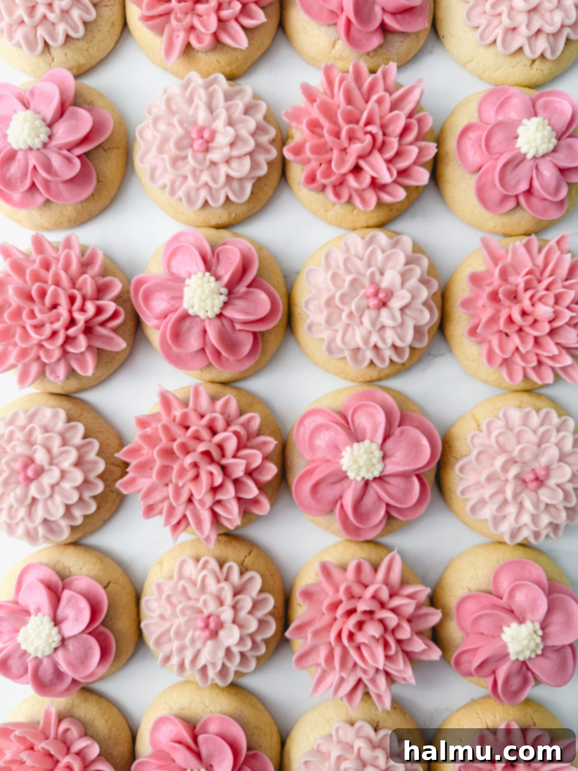 Mini frosted sugar cookies decorated with gradient buttercream flowers for a baby shower.