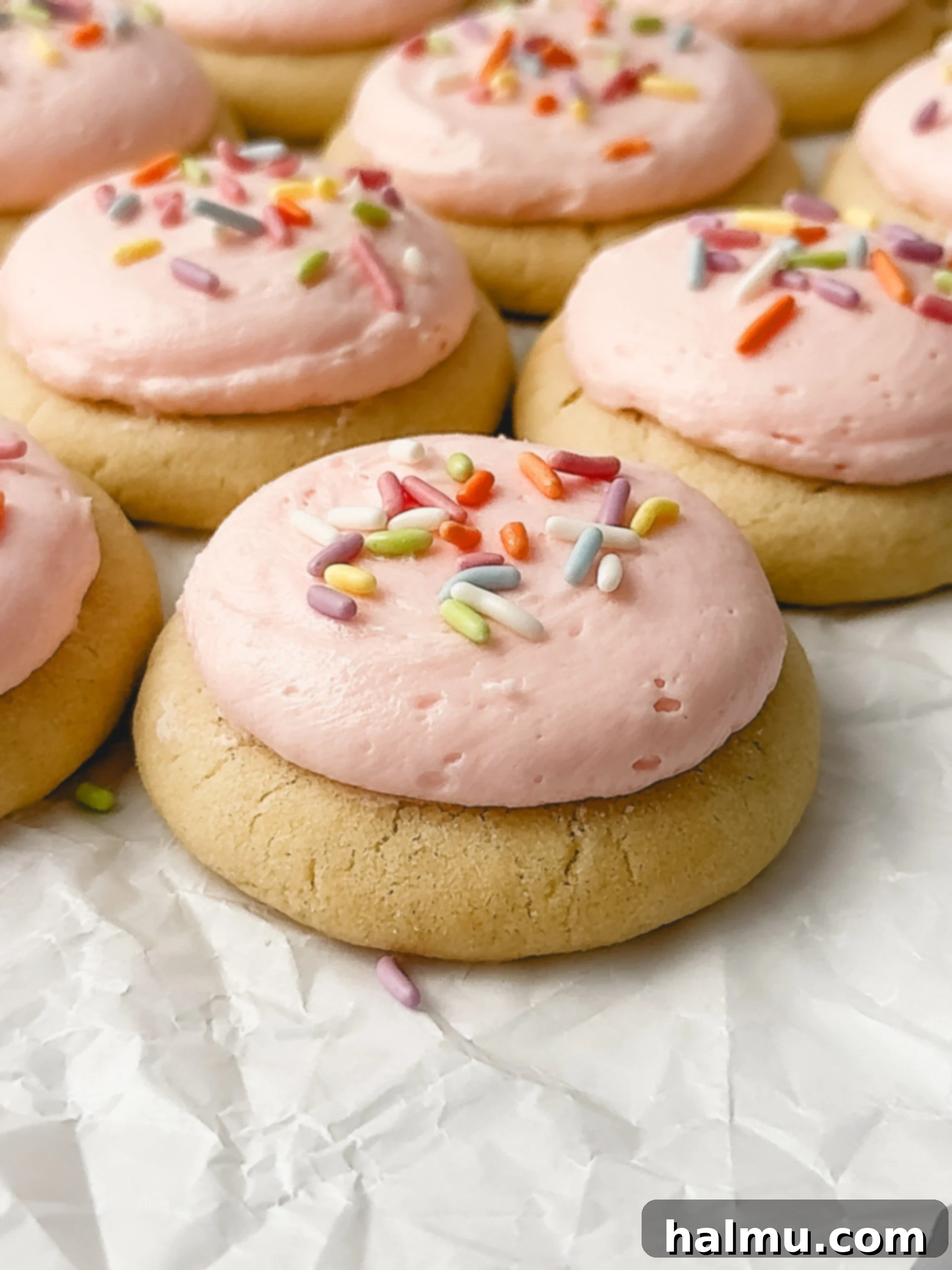 A selection of mini frosted sugar cookies with various frosting colors and sprinkles.