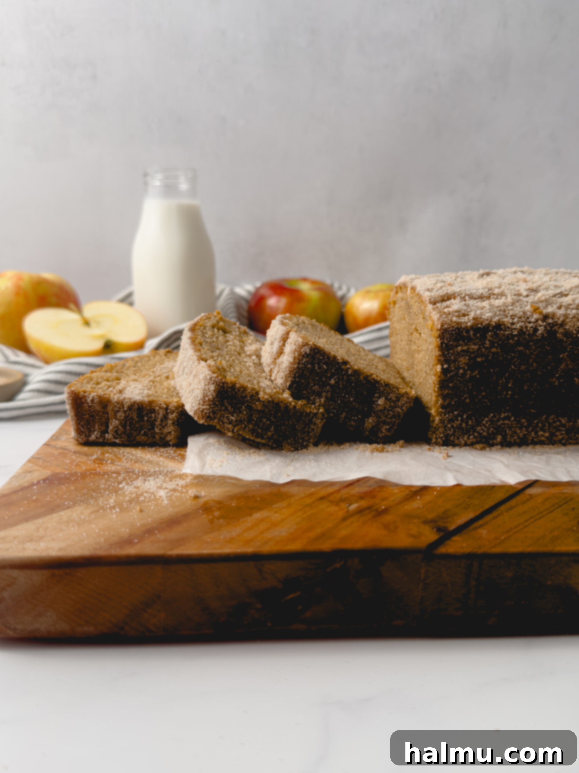 Spiced Apple Cider Doughnut Loaf 9 A stunning top-down view of the whole Apple Cider Donut Loaf Cake, beautifully baked and dusted with cinnamon sugar, sitting on a wooden cutting board.