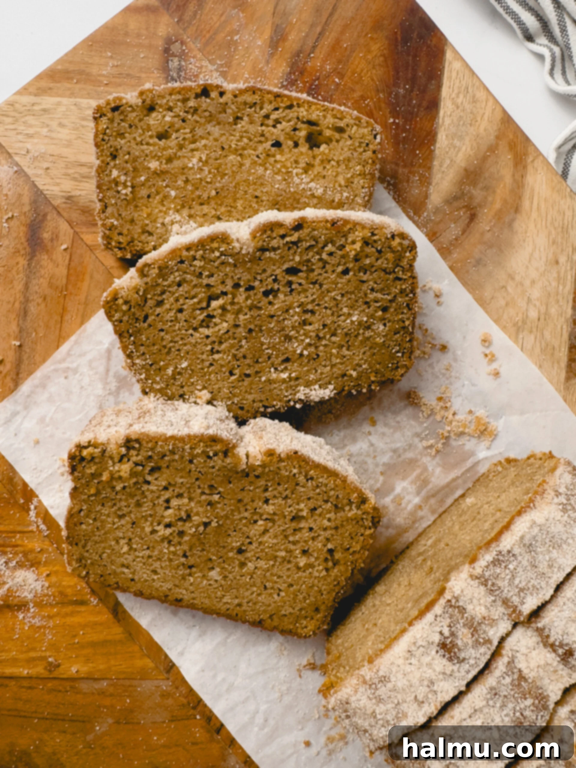 Spiced Apple Cider Doughnut Loaf 8 An inviting top-down shot of the Apple Cider Donut Loaf Cake, showcasing its perfect golden-brown crust and glistening cinnamon sugar topping, resting on a rustic wooden board.