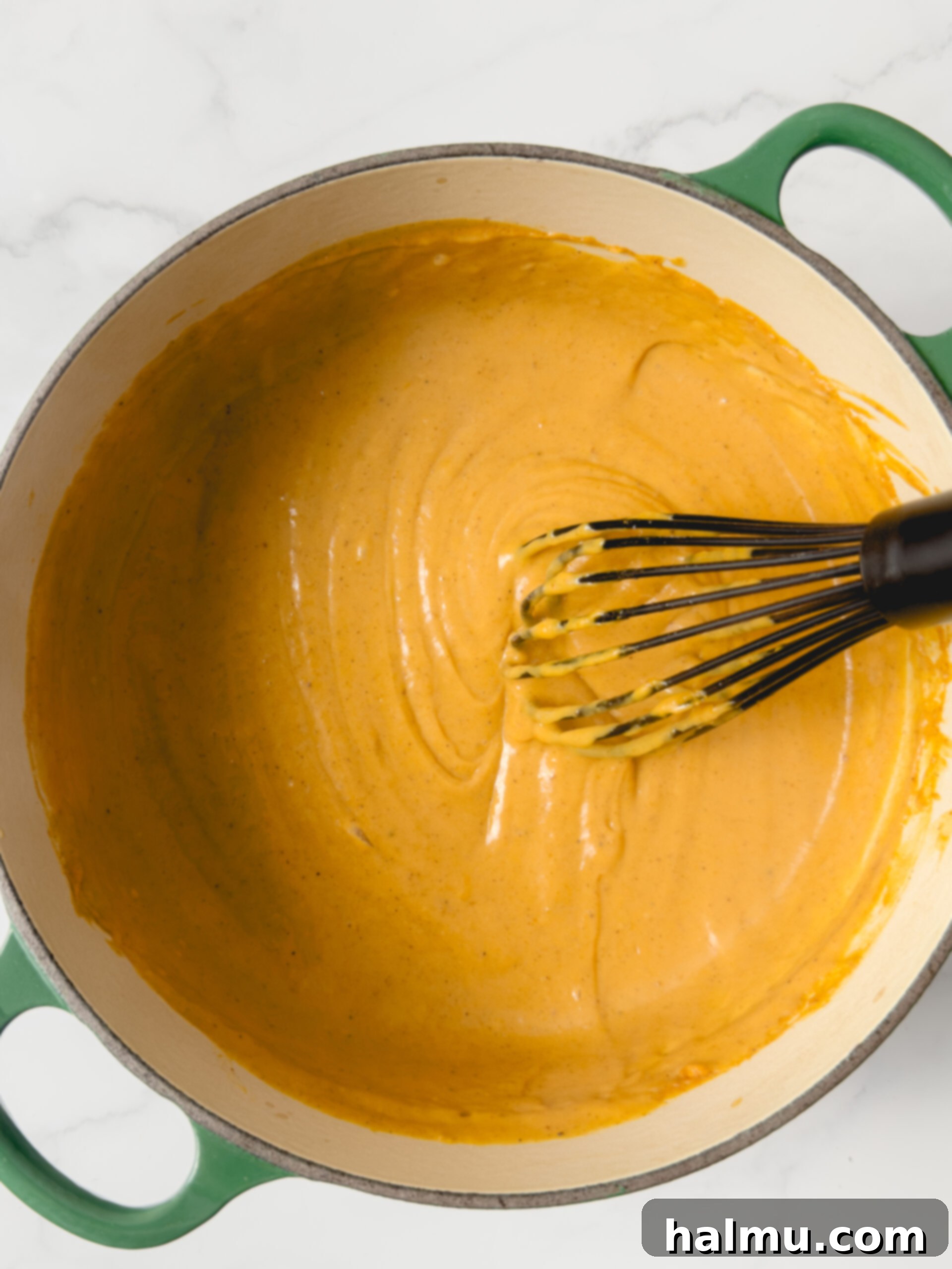 Ingredients for pumpkin pudding being whisked in a saucepan on the stove.