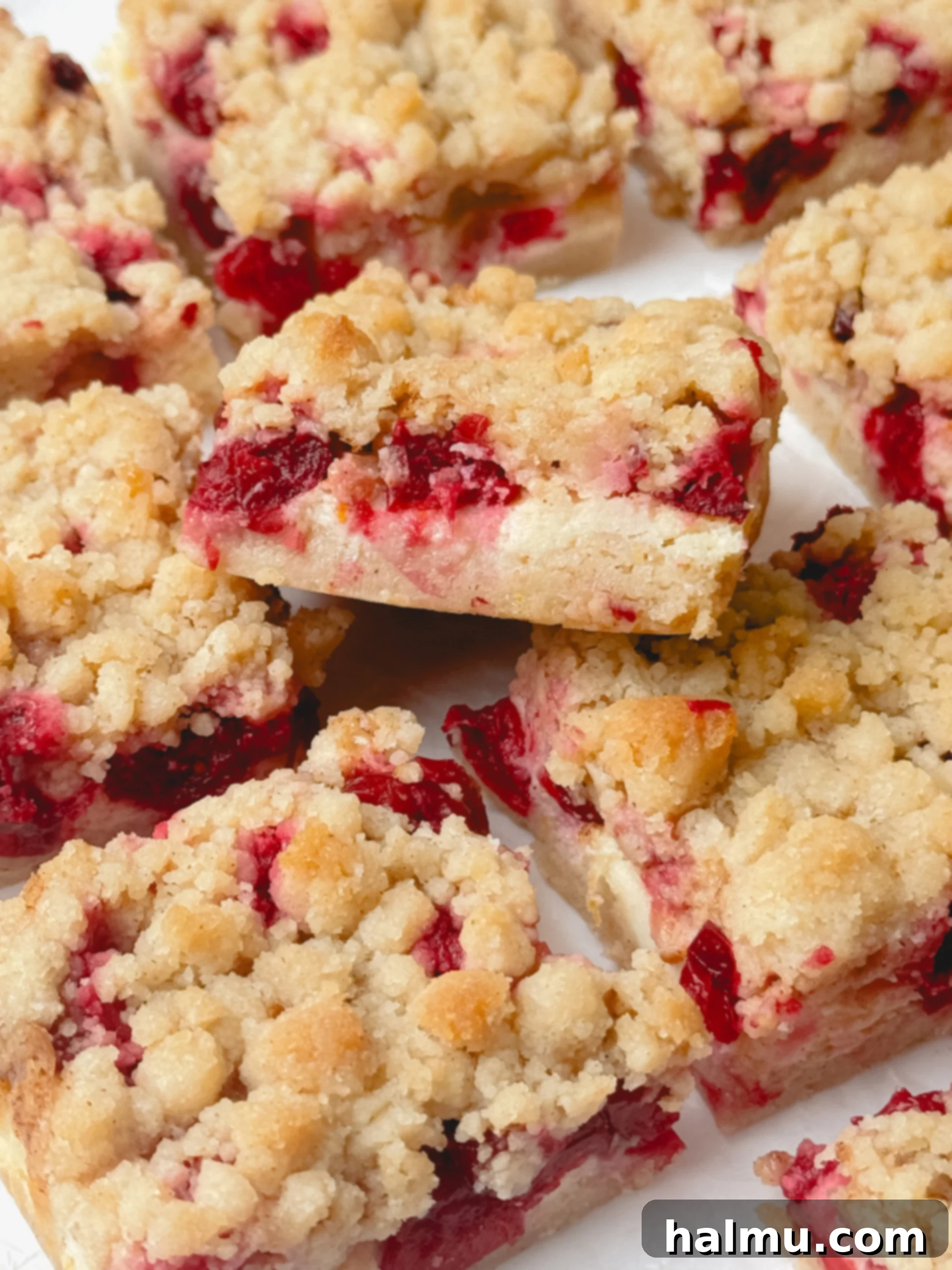Stacked cranberry cheesecake bars with a bite taken from one, showing the layers.