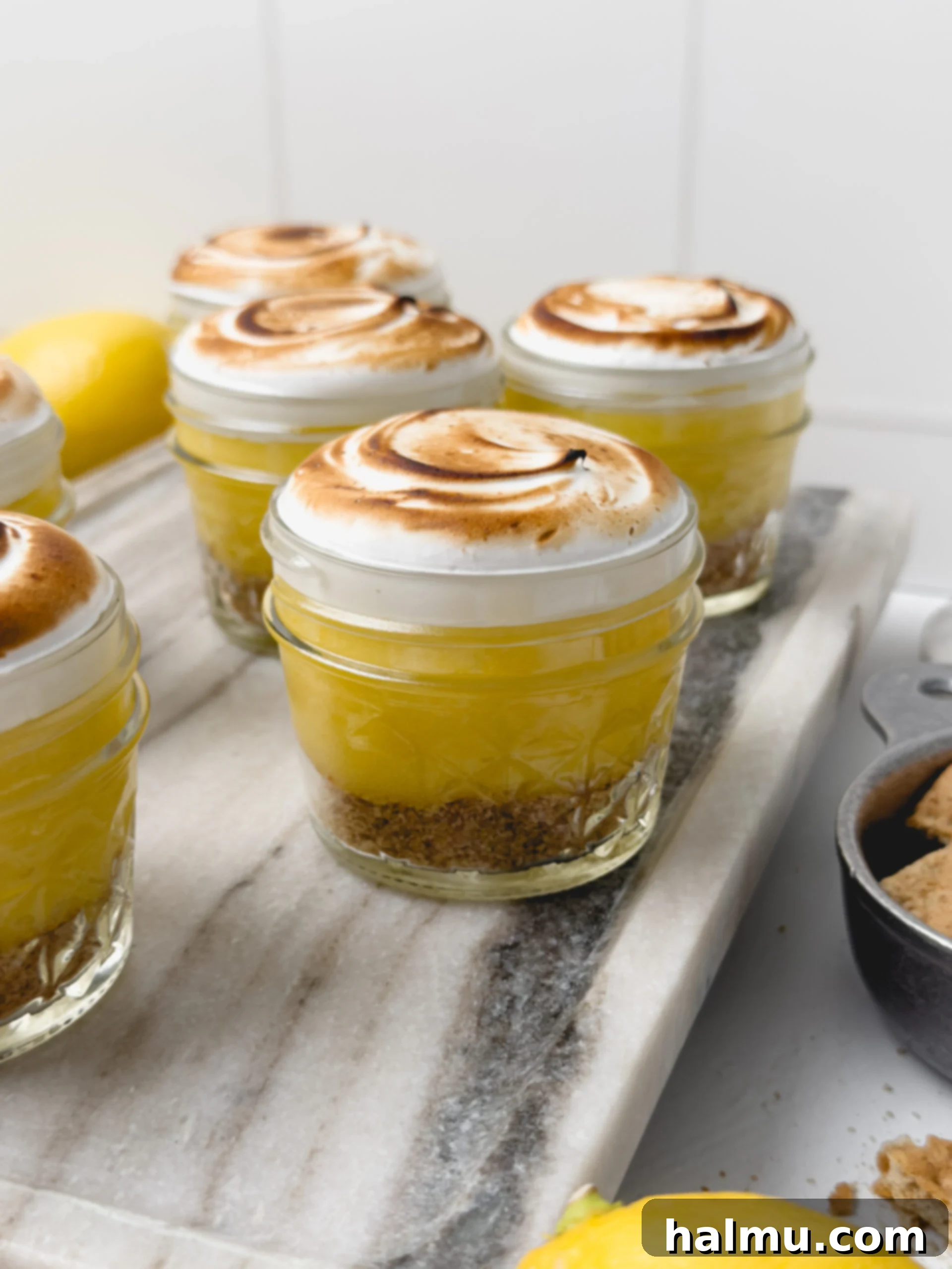 Close-up of three Lemon Meringue Pie Cups, showing layers of graham cracker crust, lemon curd, and toasted meringue.