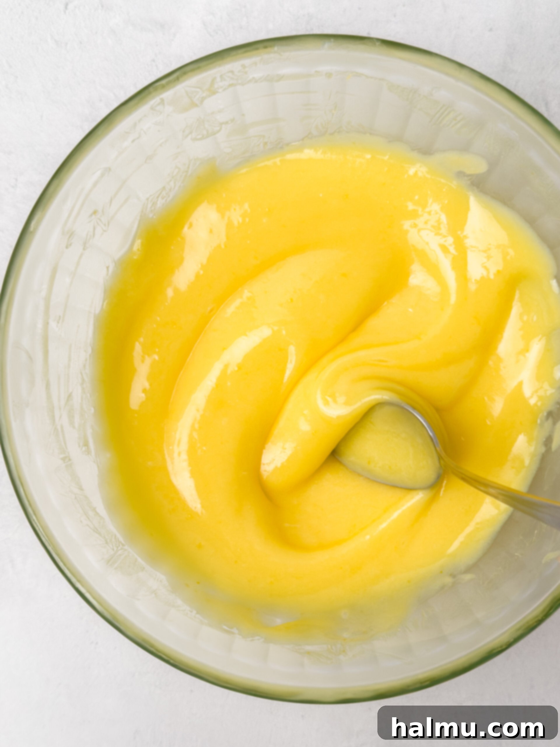 Zesty Lemon Cream 7 Two jars of homemade lemon curd, one with a spoon, highlighting its creamy texture.