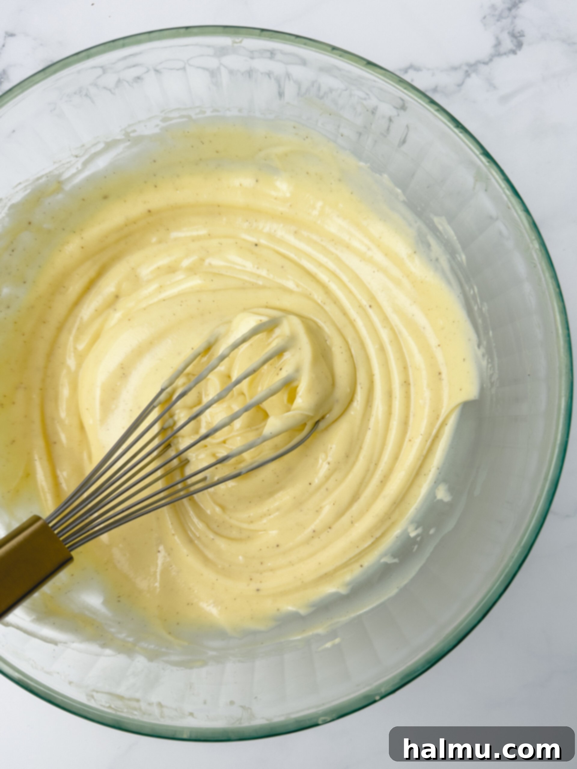 Velvety Vanilla Dream 10 A close-up of smooth, luscious vanilla pastry cream in a bowl with a spoon, highlighting its perfect consistency.