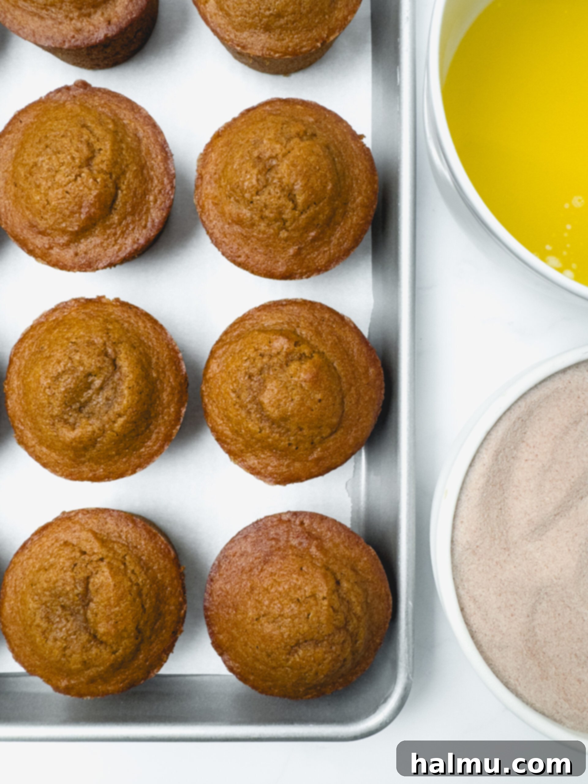 Pumpkin Spice Donut Muffins 5 Freshly baked Pumpkin Donut Muffins cooling in a muffin tin.