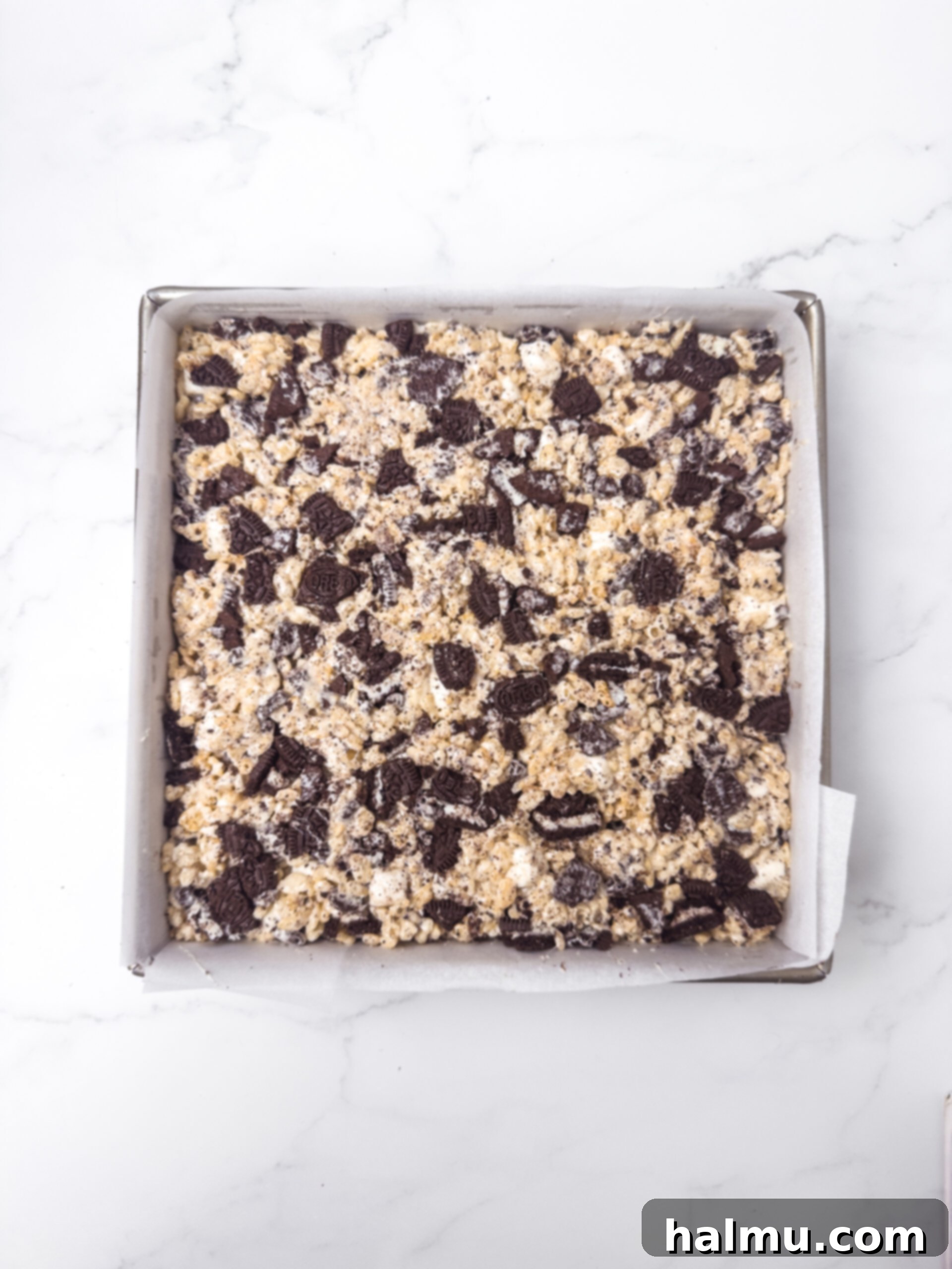 Oreo Krispie Treats 6 Oreo Rice Krispie Treat mixture pressed into a baking pan with extra Oreo chunks on top.