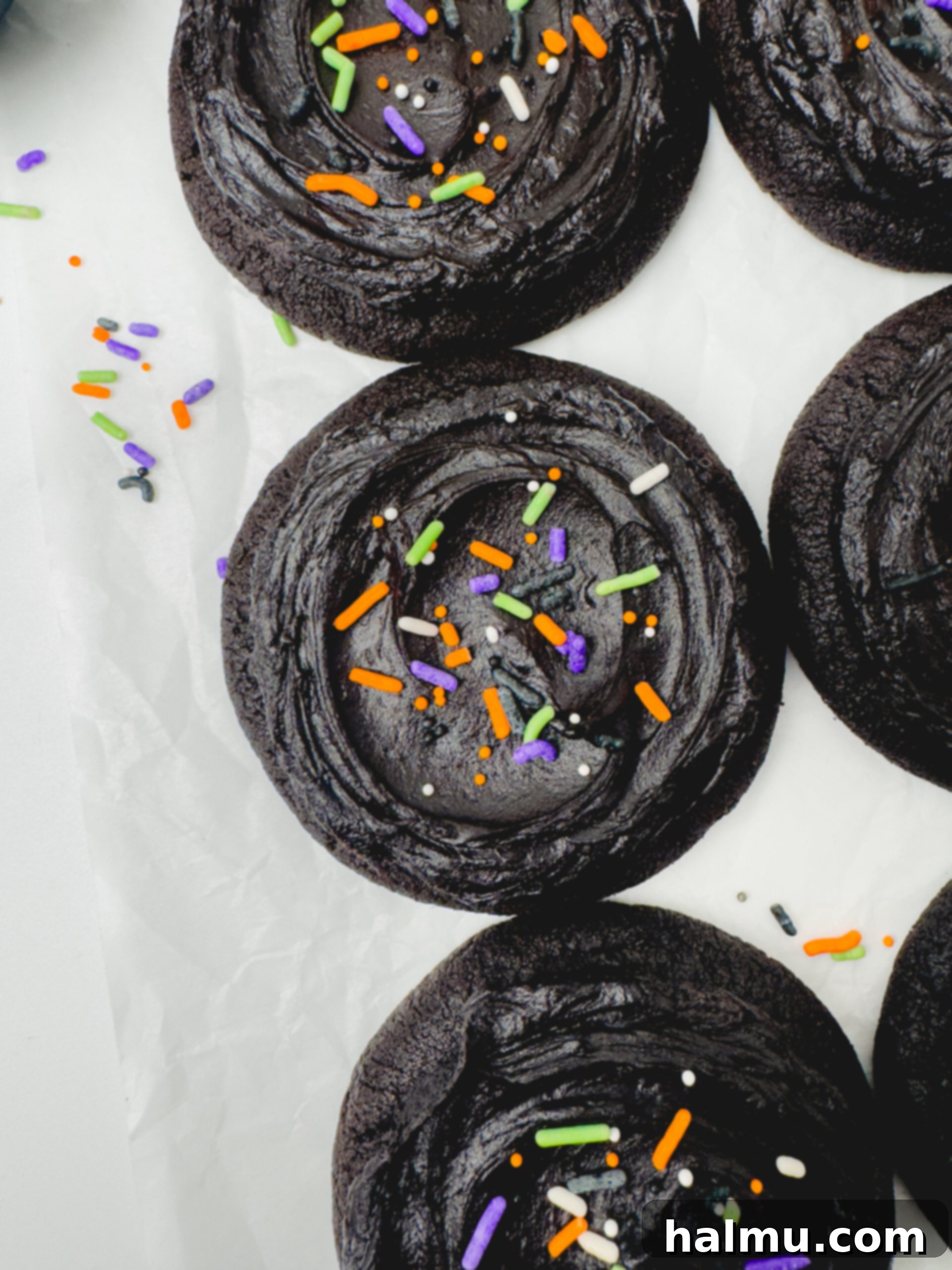 A perfectly frosted Frosted Black Cocoa Cookie topped with a variety of colorful sprinkles, ready for a party.