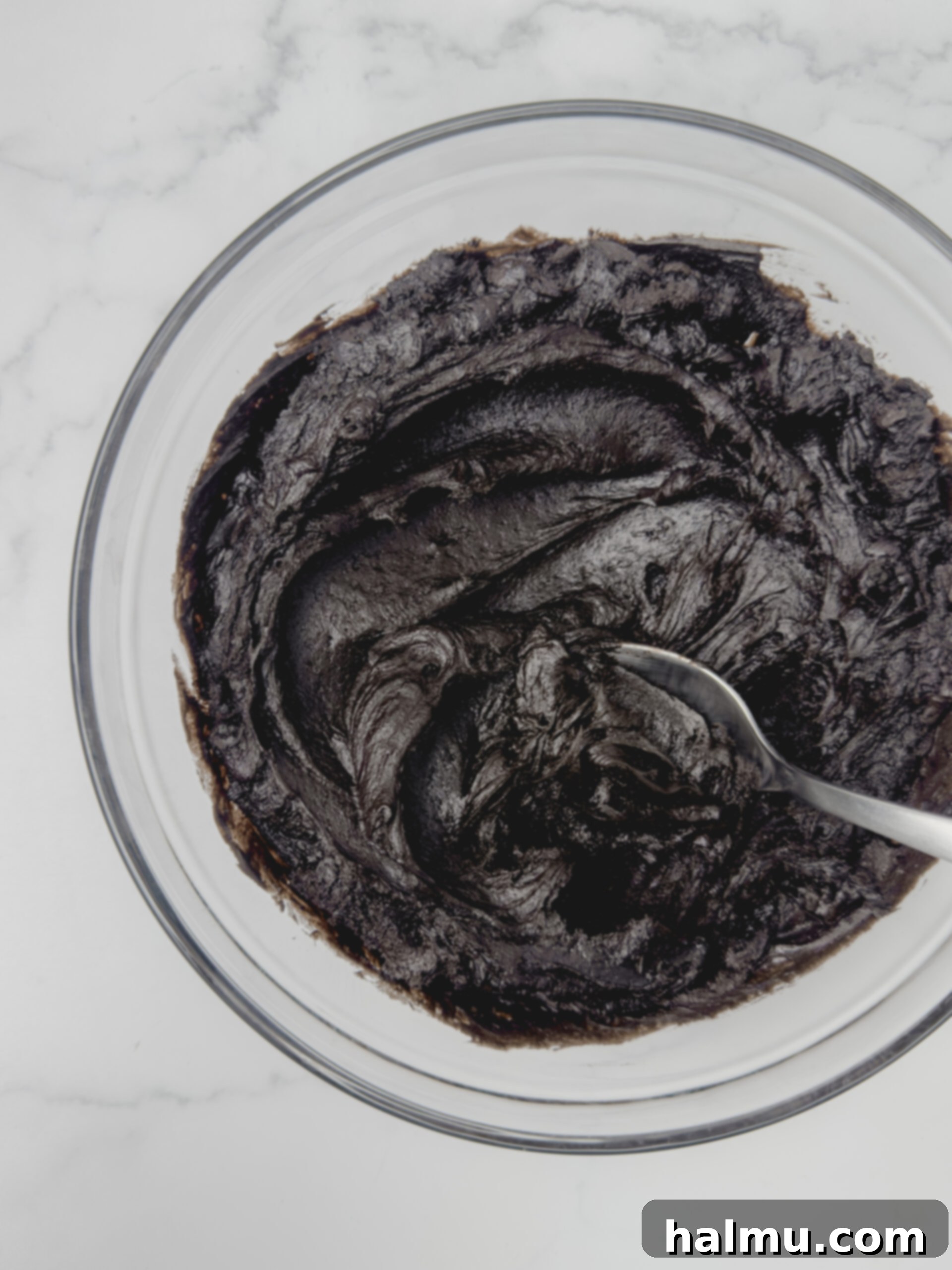 A frosted black cocoa cookie topped with colorful Halloween sprinkles, ready to be enjoyed.