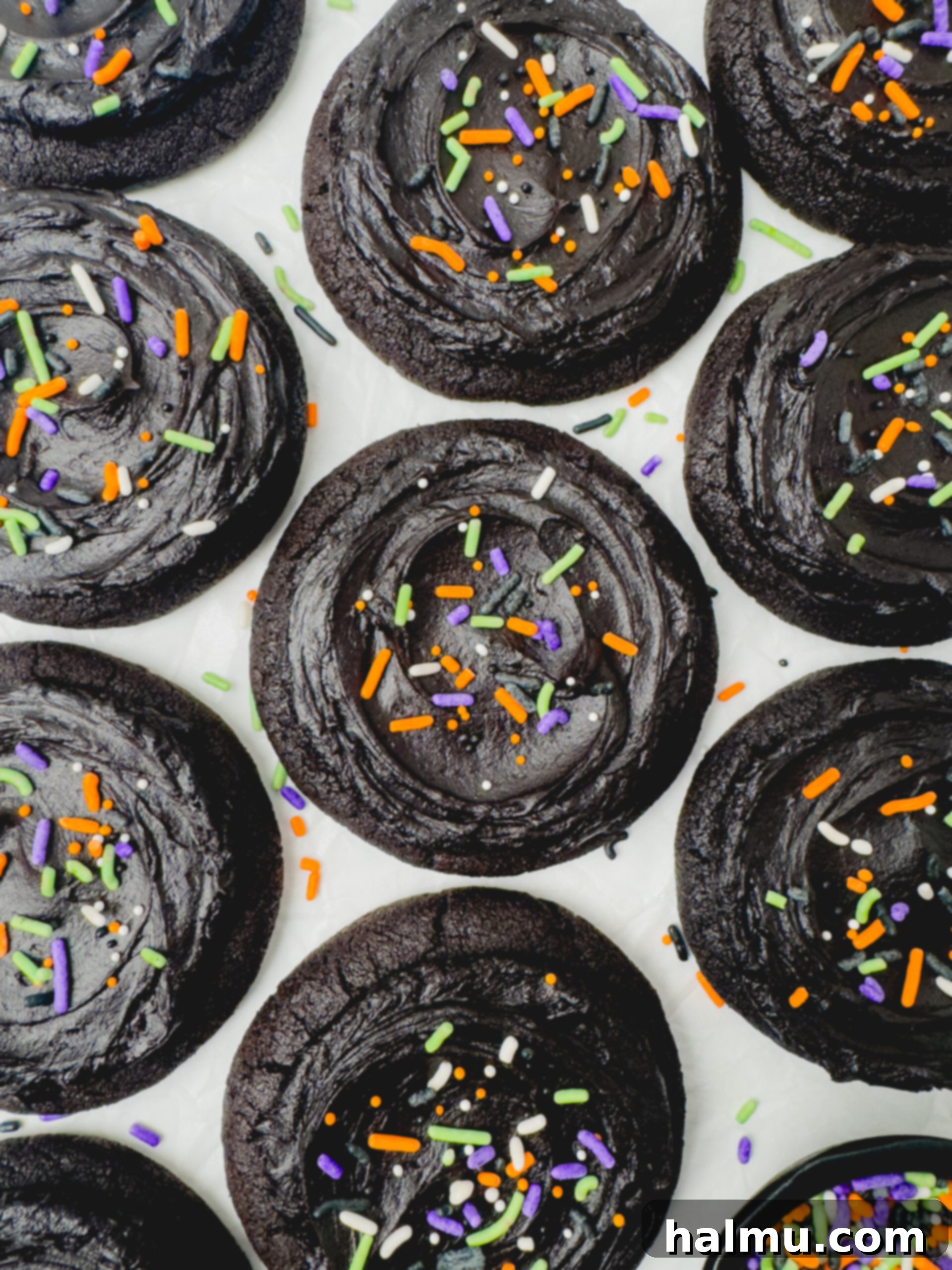 A stack of Frosted Black Cocoa Cookies, some with Halloween sprinkles, showcasing their soft texture and rich frosting.