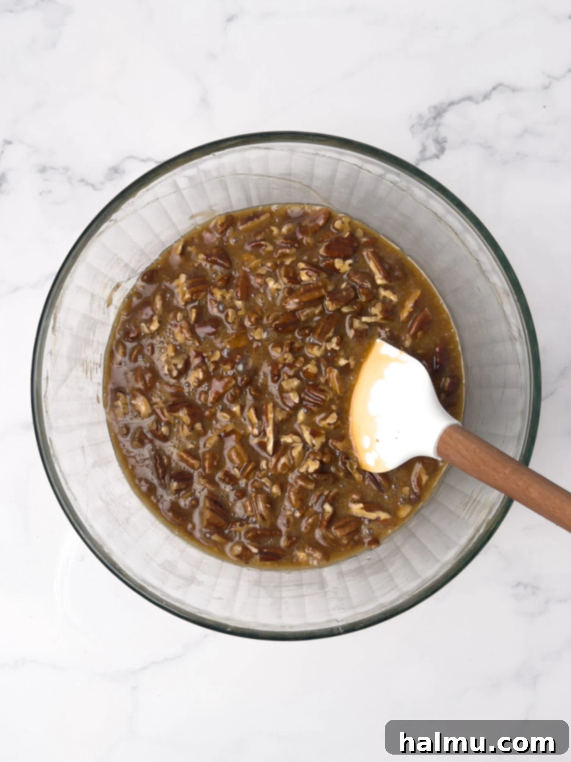 Pecan pie filling mixture in a bowl with chopped pecans.
