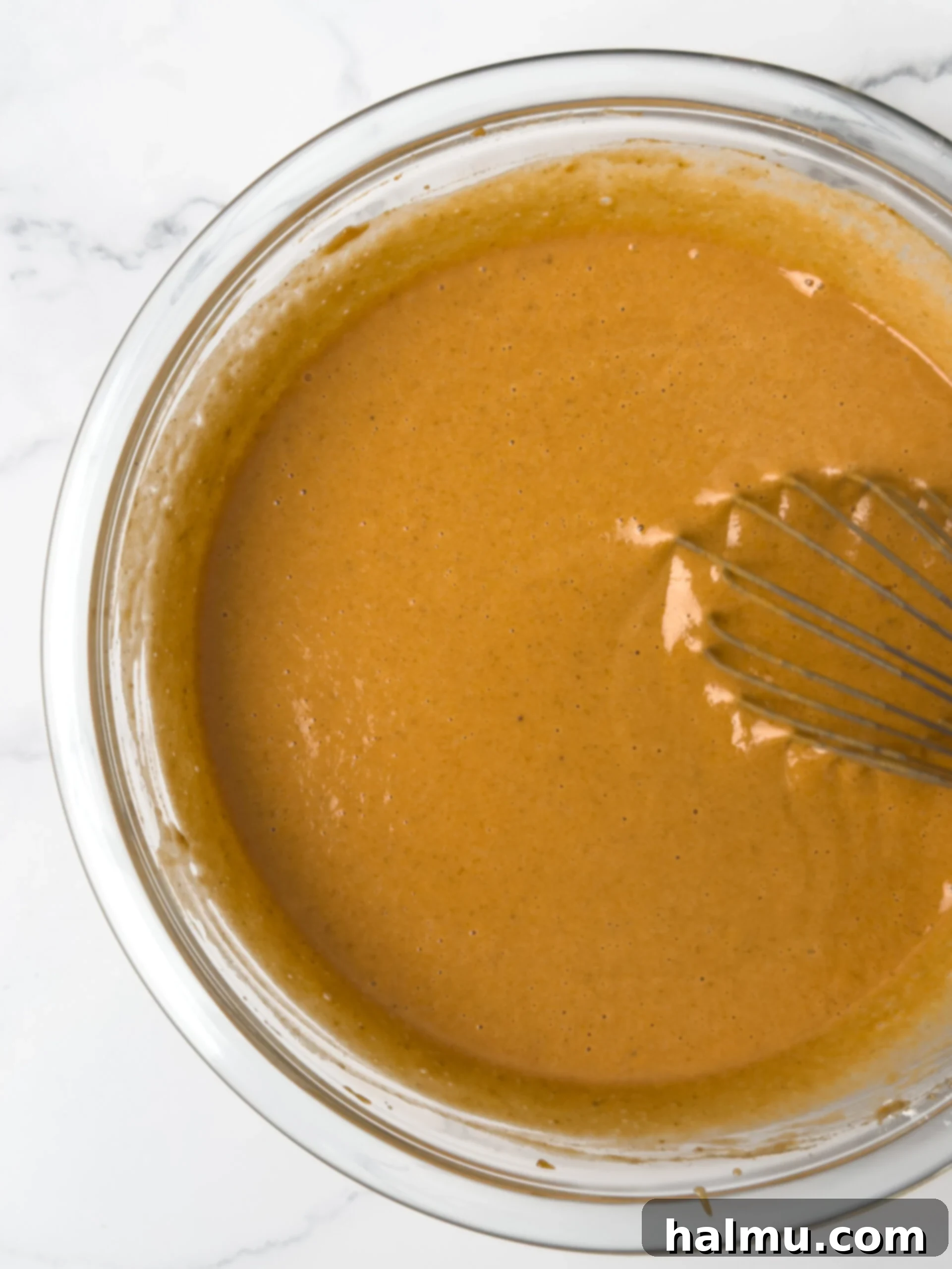 The smooth, spiced pumpkin pie filling being whisked in a large bowl, ready for baking.