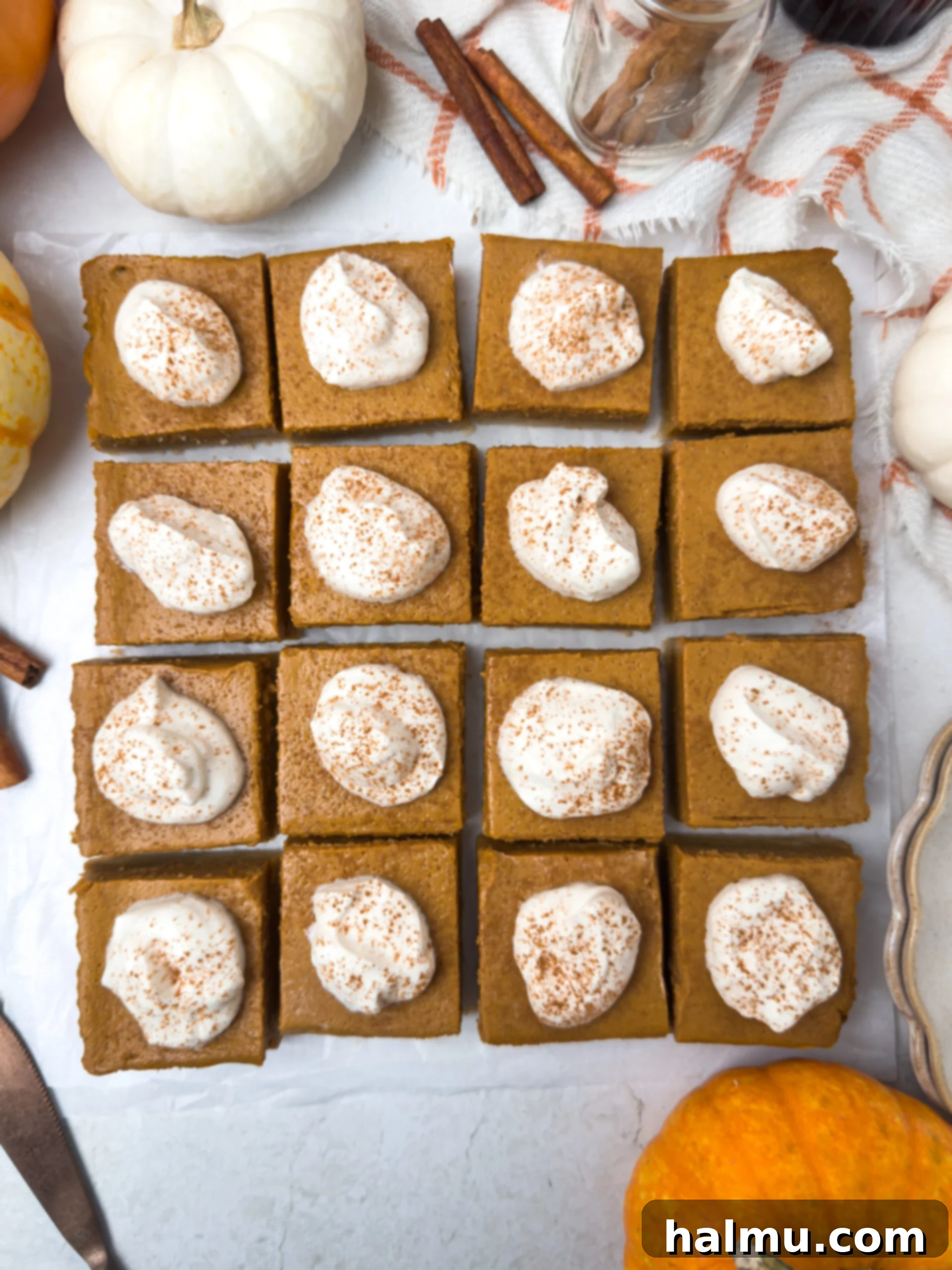 A close-up shot of a pumpkin pie bar, perfectly sliced, with a swirl of maple whipped cream and a sprinkle of cinnamon on top.